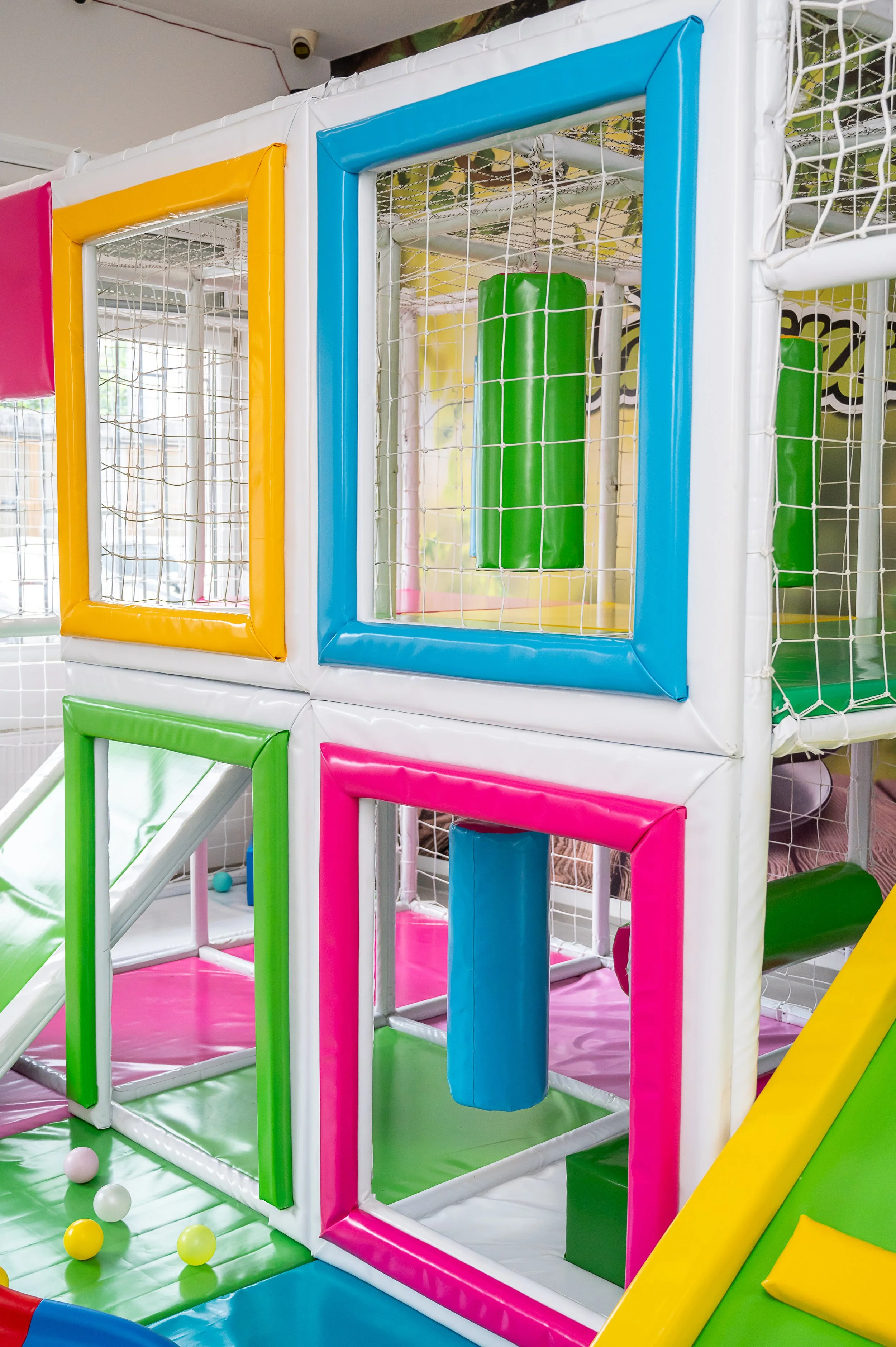 Colorful indoor soft play structure with climbing frames and padded tubes.