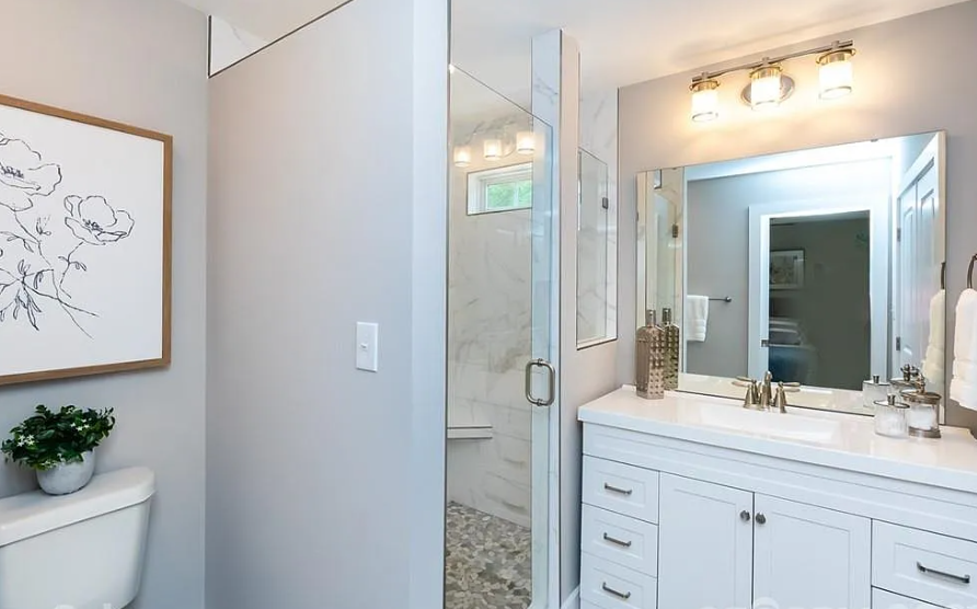 Modern bathroom with a white vanity, large mirror, shower with marble walls, and simple wall decor