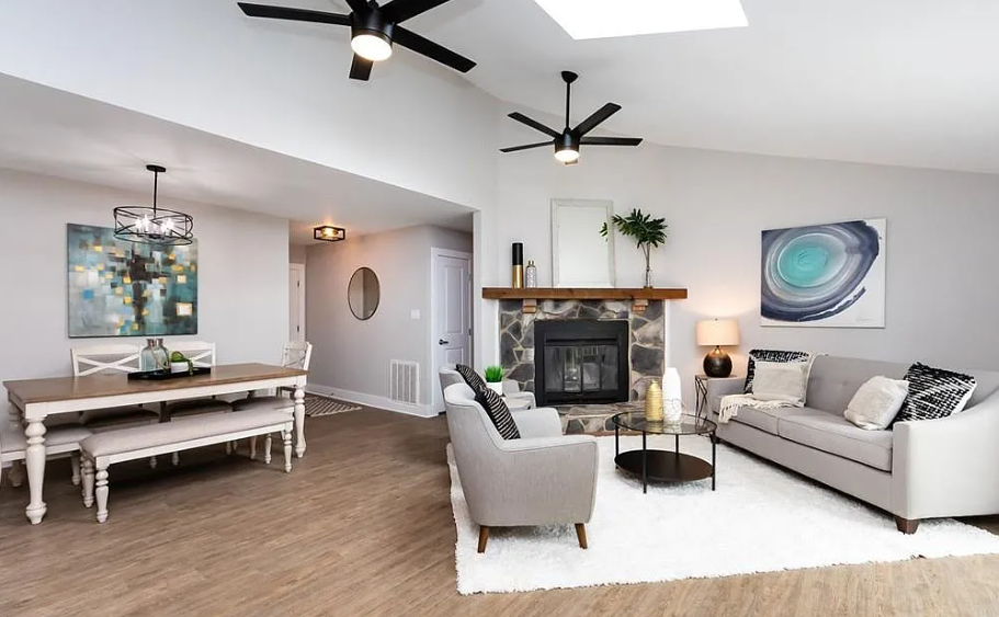Modern living room with white walls, a stone fireplace, two light gray sofas, and abstract artwork