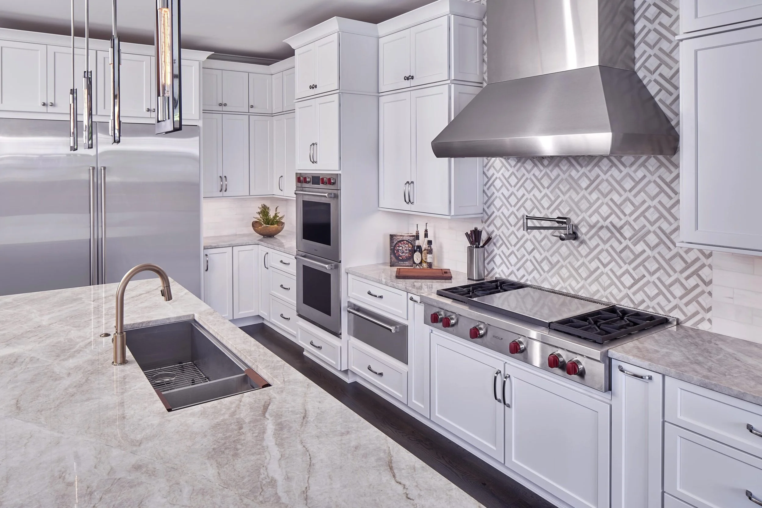 Modern kitchen with white cabinets, stainless steel appliances, a marble countertop island, and a decorative backsplash.