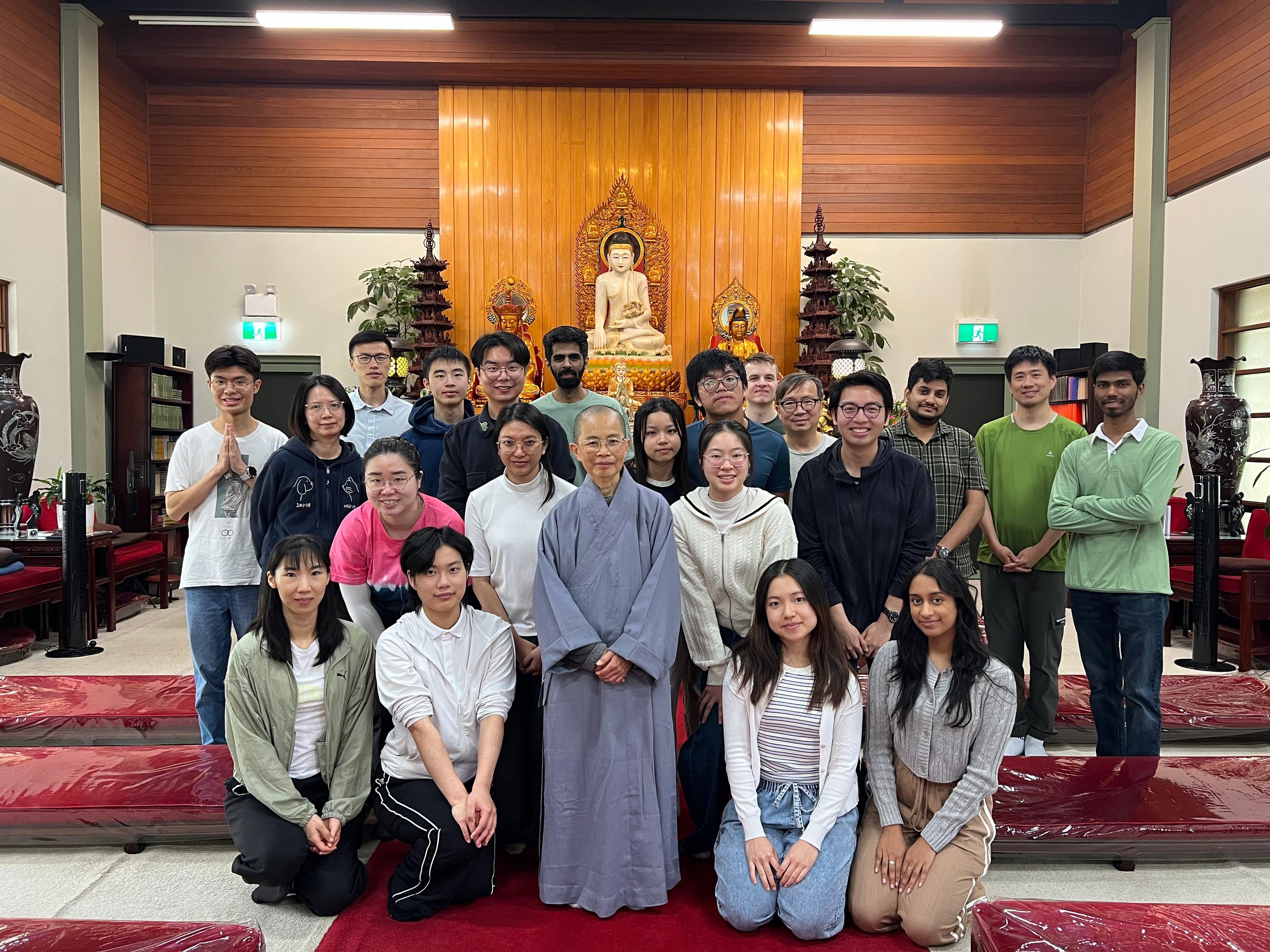 UniBodhi posing together inside a Buddhist temple with a statue of Buddha on the altar behind them.
