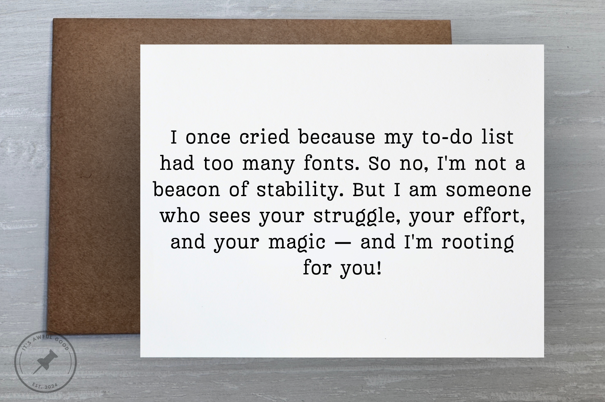 A letter with an inspiring message on a white card placed on a brown envelope, on a gray wooden surface.