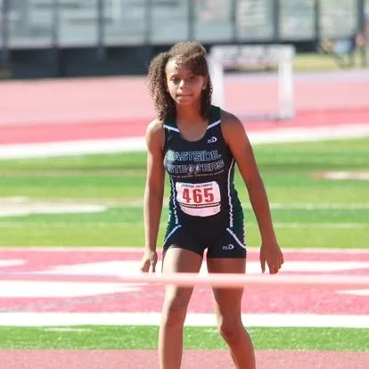 Young girl in athletic wear standing at finish line on track