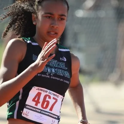 Young female athlete in black sportswear running outdoors during a race, wearing a bib number 467.