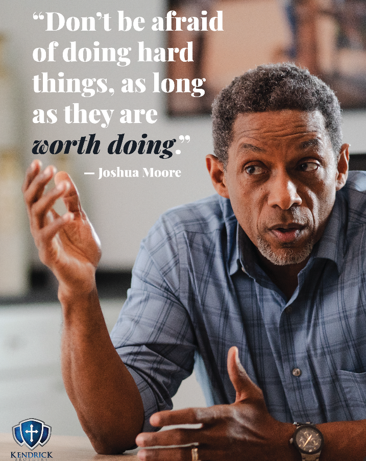 An older man with curly hair sitting at a table, gesturing with one hand, speaking thoughtfully. There is a quote overlay that says, 'Don't be afraid of doing hard things, as long as they are worth doing.'