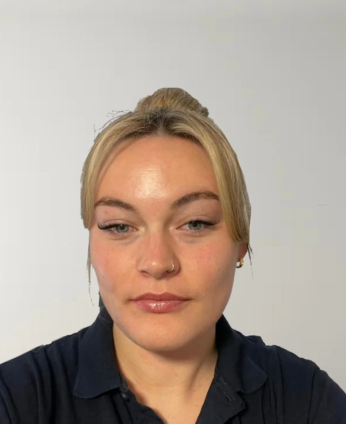 Scottish-Caucasian woman with blonde hair tied up in a bun wearing a black top.