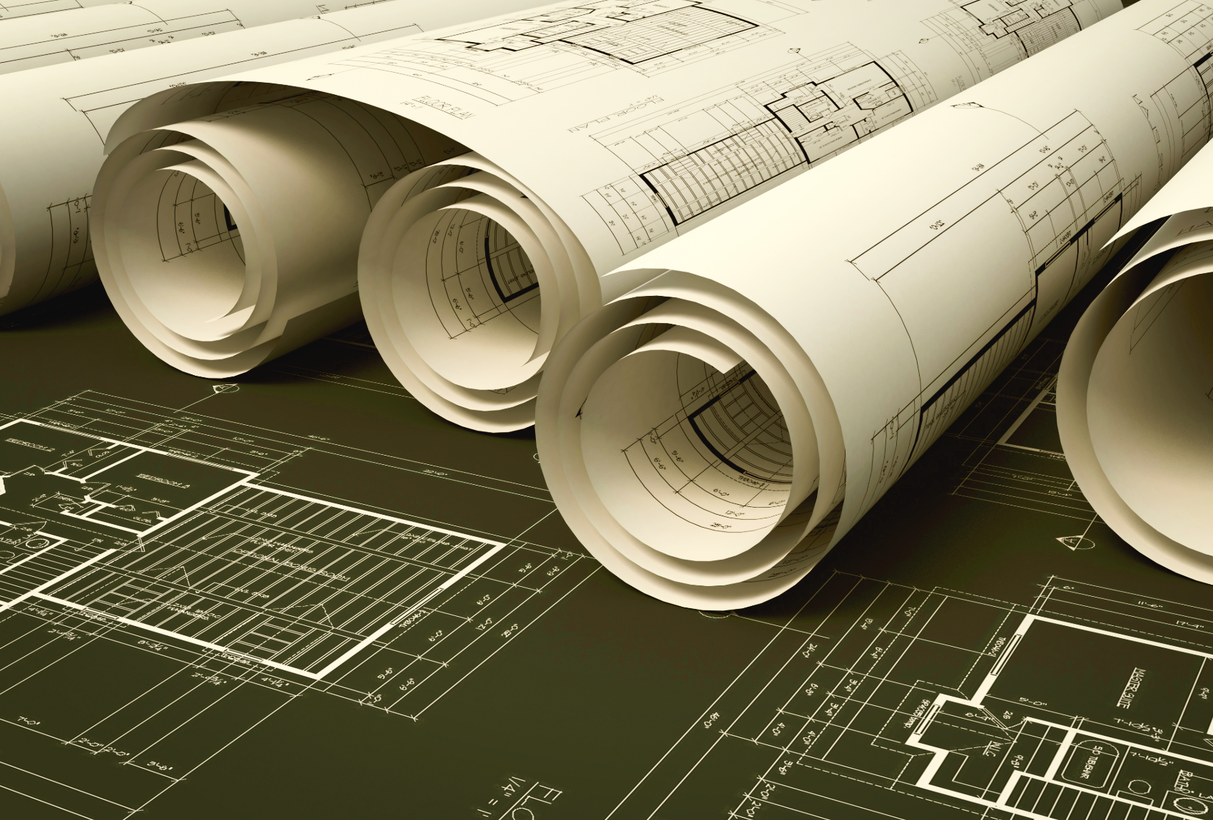 Rolled architectural blueprints on top of a detailed floor plan.