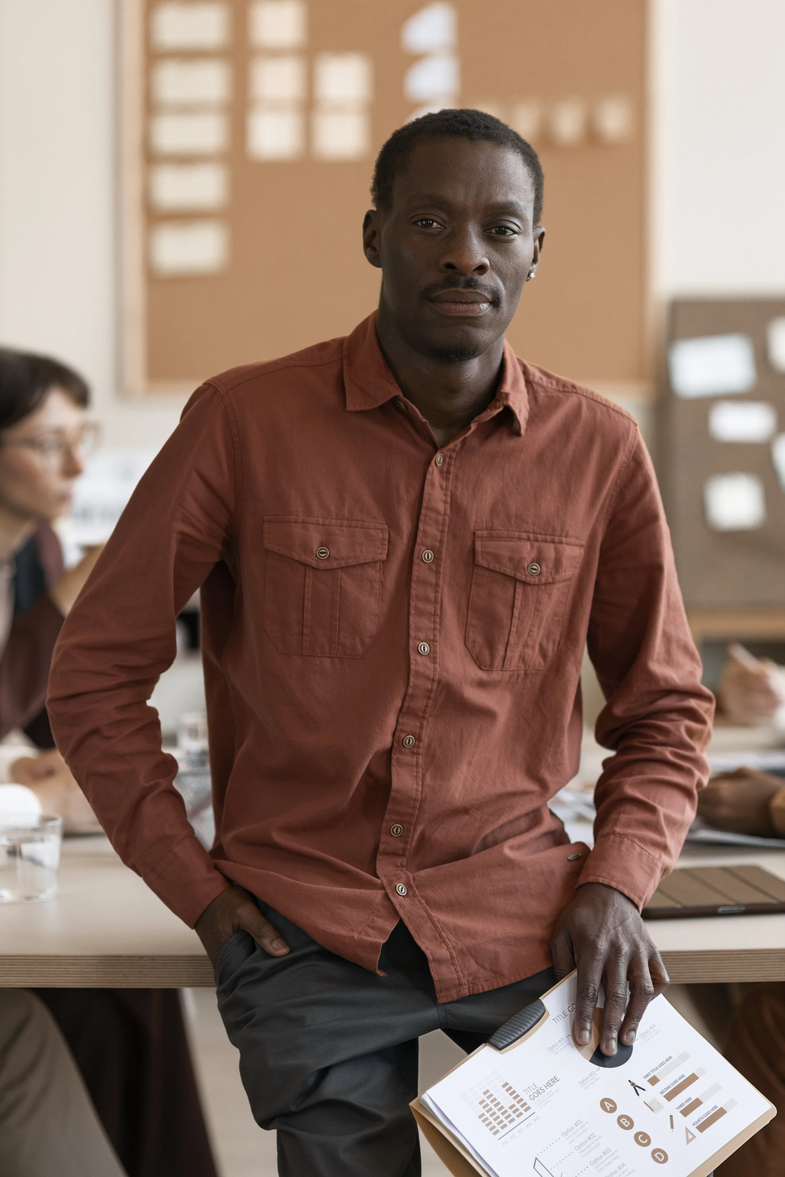 Professional man leading a discussion in a team setting, holding strategic documents in a workplace environment.