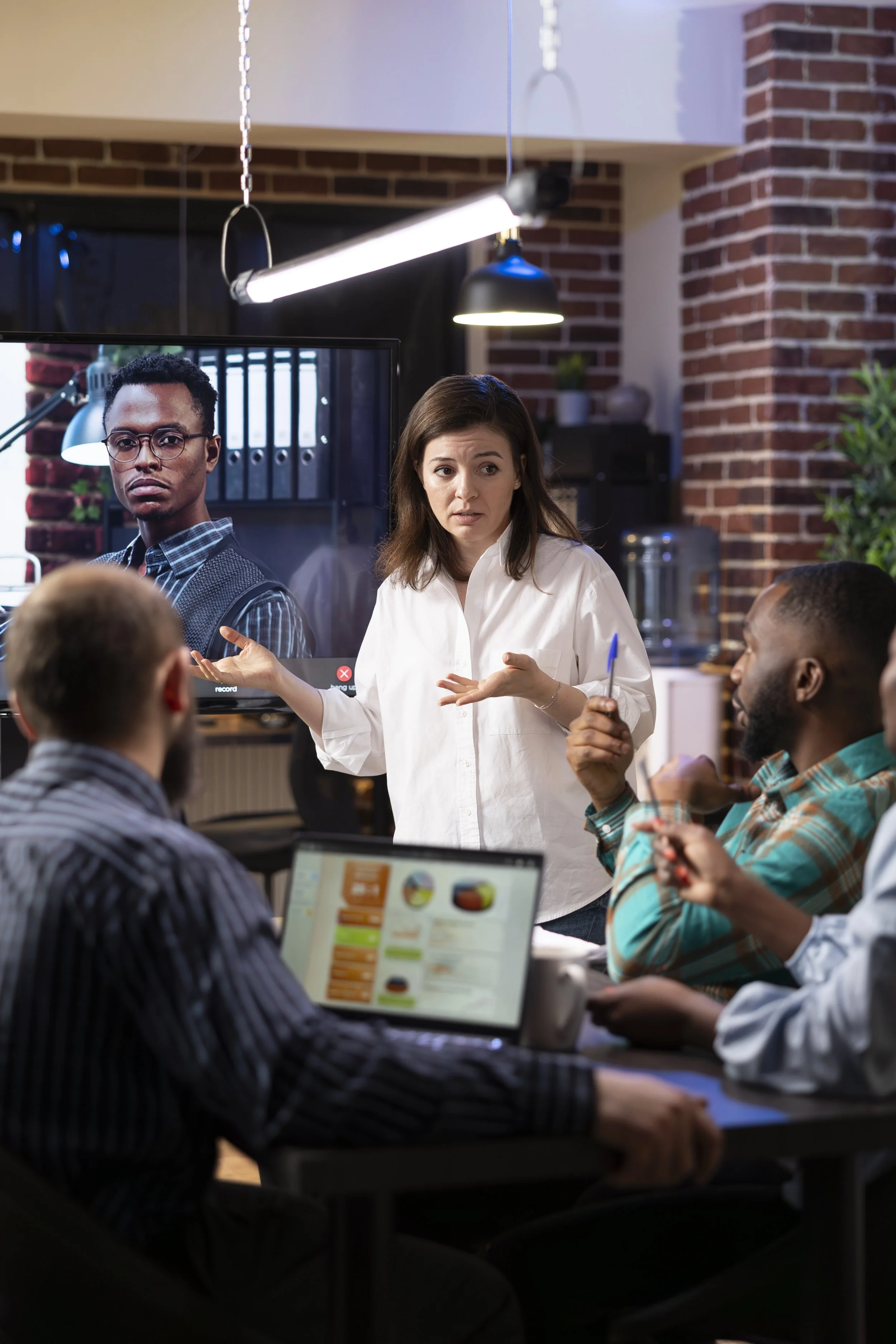 Facilitator leading a team discussion in a collaborative workspace with both in-person and remote participants.