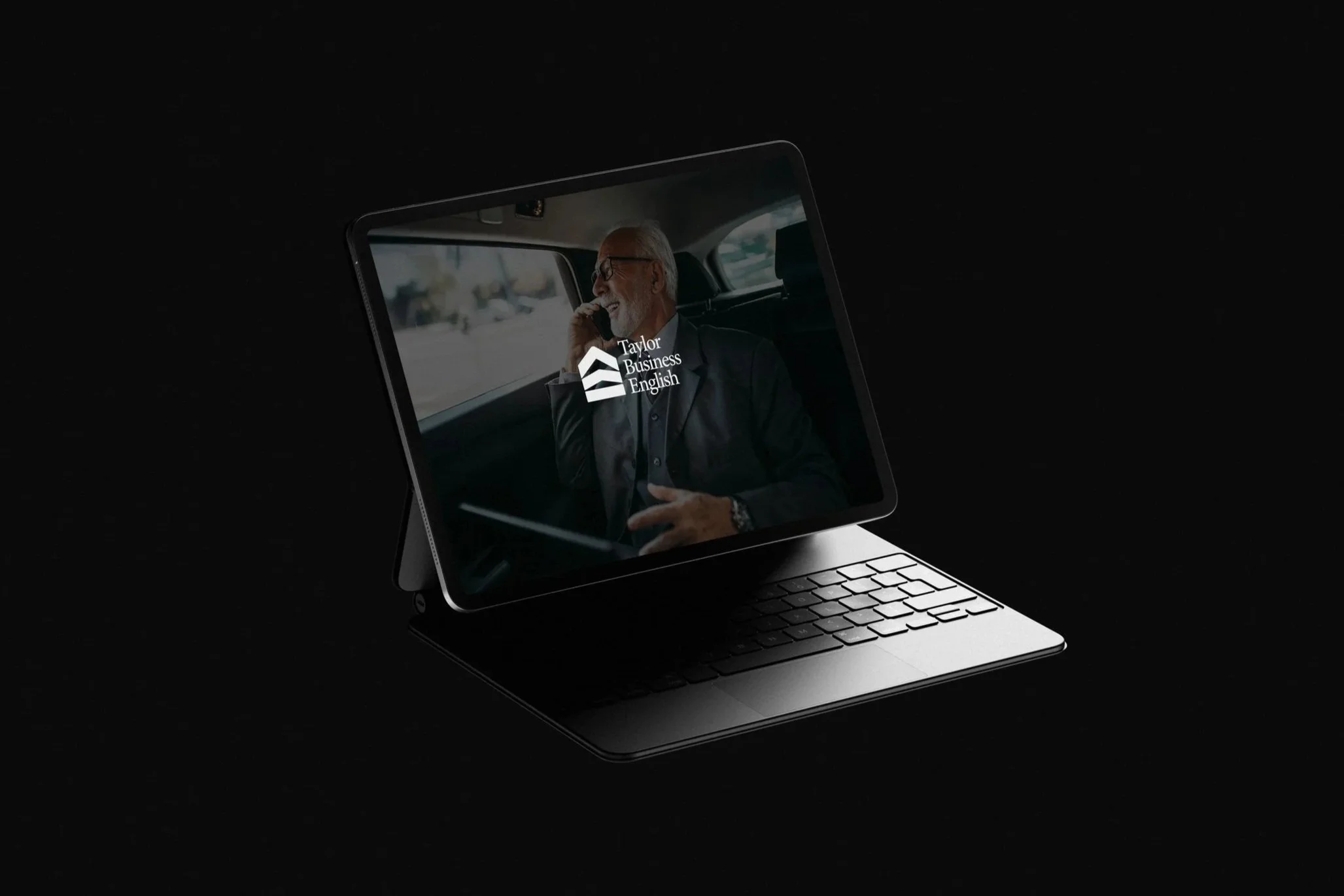 Schermo di un laptop con un uomo d'affari anziano in abito che parla al telefono, logo di Taylor Business English sopra