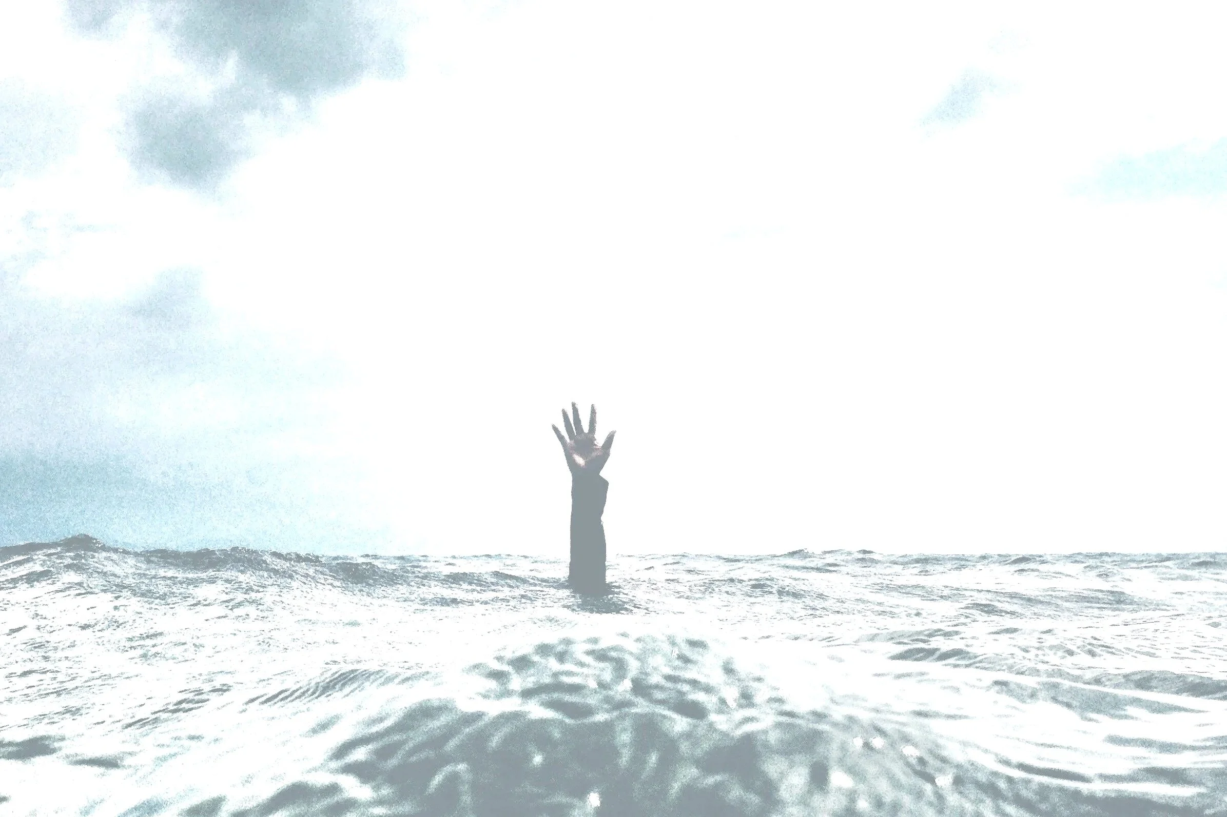 An arm and hand reaching out of the ocean waves, with a cloudy sky above.