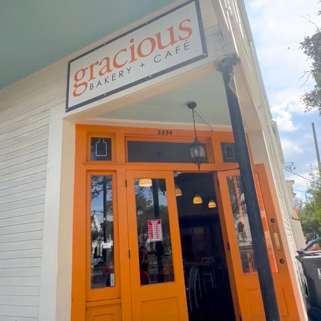 Exterior of Gracieux Bakery and Café with orange door and window frames, hanging lantern, and street view.