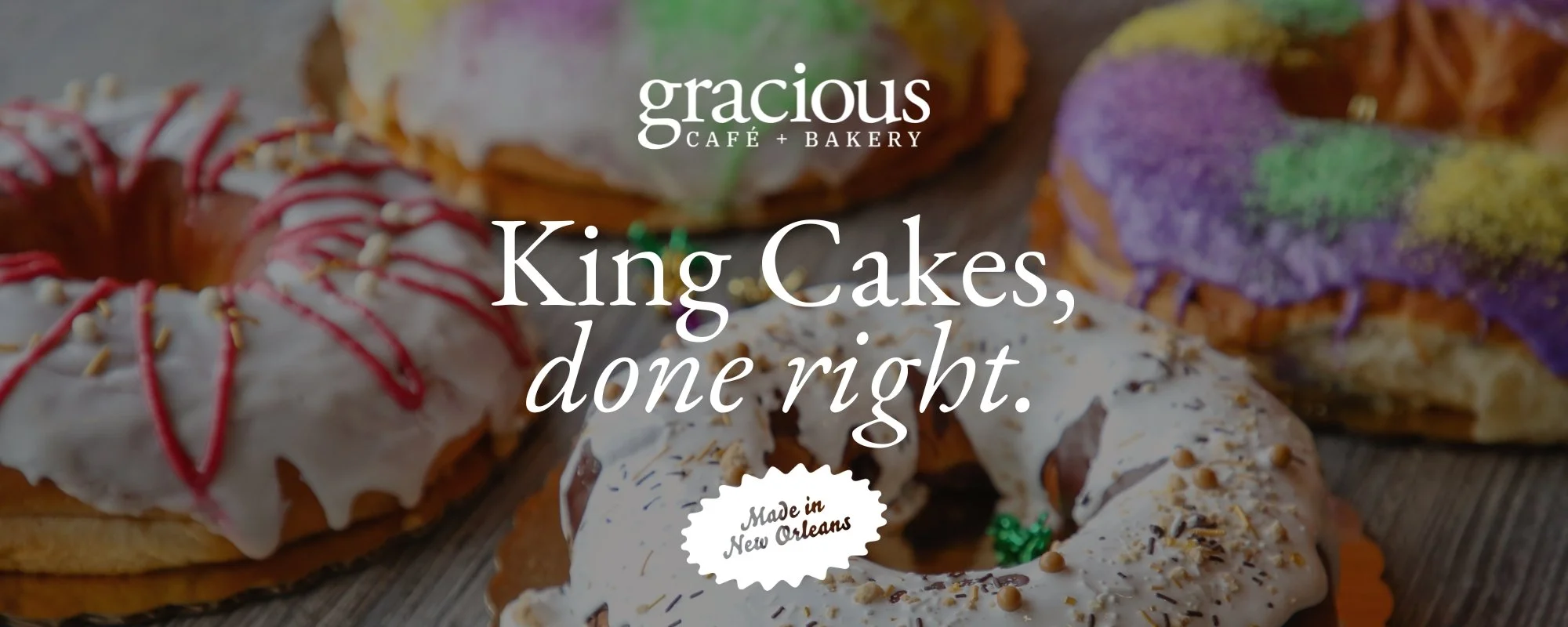 Assorted King Cakes with colorful icing, sprinkles, and decorations, typical for celebrations, on a wooden surface.