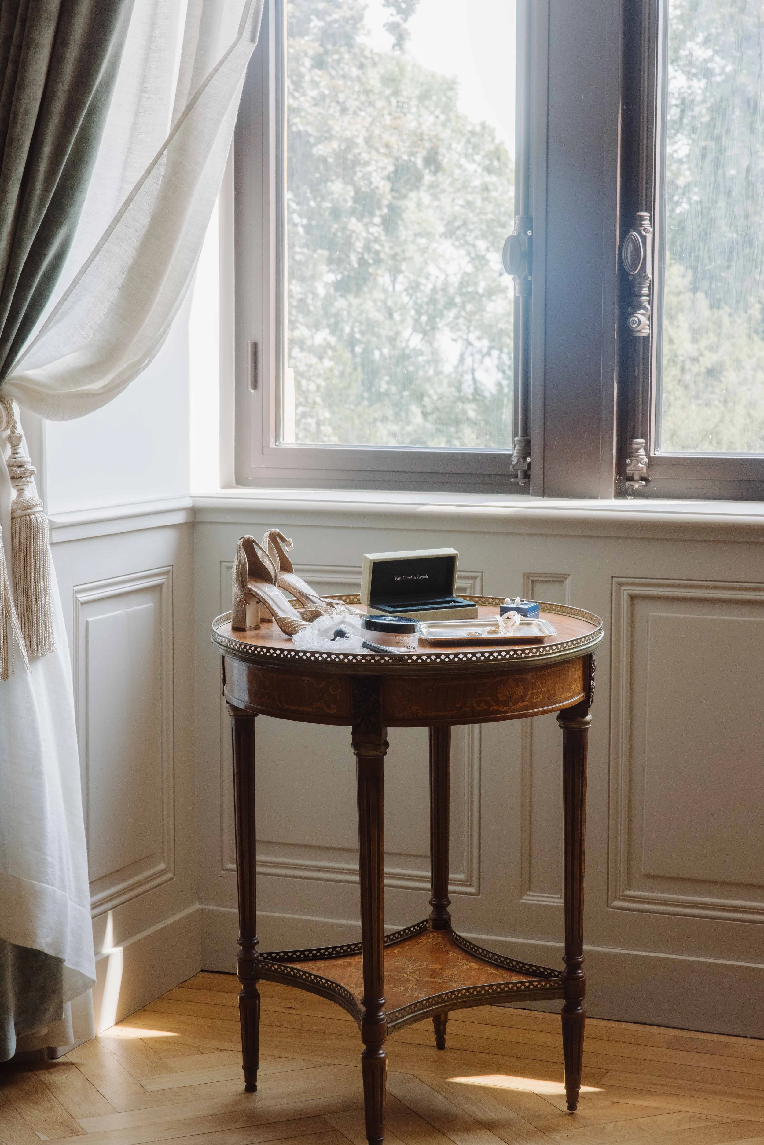 Chaise ancienne en bois avec chaussures à talons sur le siège, boîte de souvenirs, et accessoires, près d'une fenêtre lumineuse dans une pièce élégante. Mariage chateau de champ renard, Blacé, beaujolais, Lyon, destination wedding. préparatifs 