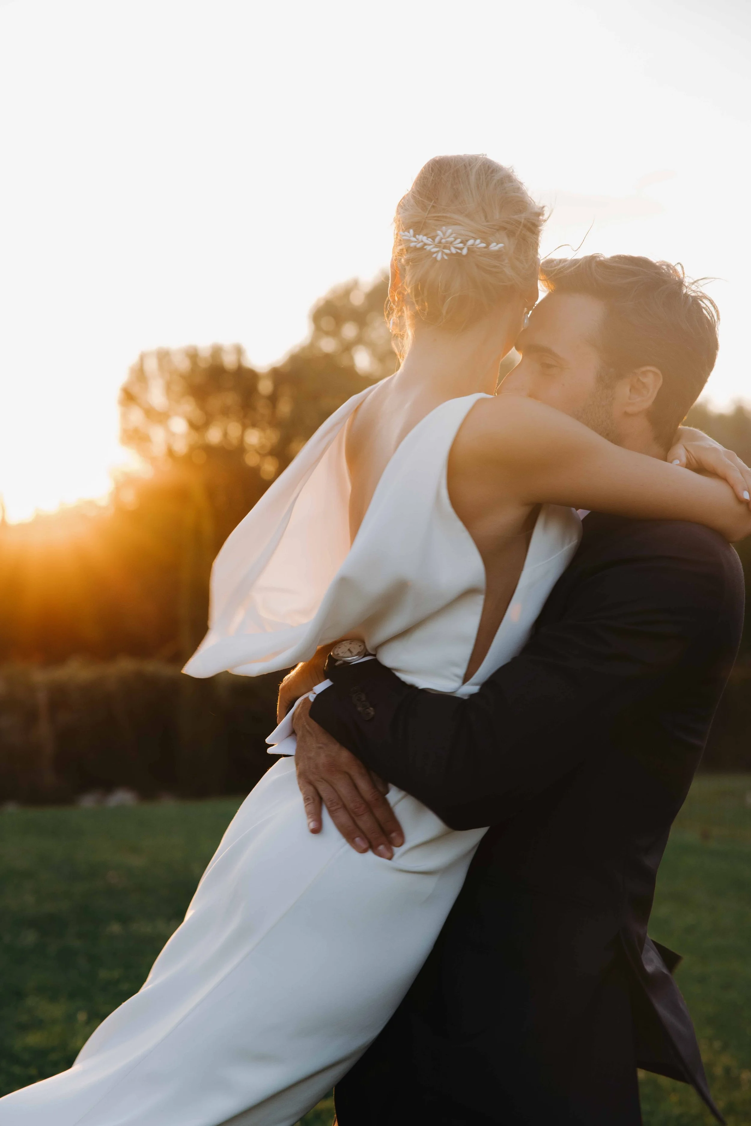 Un couple en habits de mariage partage un moment d'intimité lors d'un coucher de soleil dans un parc. Domaine du bijoutier à grignan, drome provençal, coucher de soleil, session couple, mariage religieux, cérémonie laïque, photographe mariage sud 