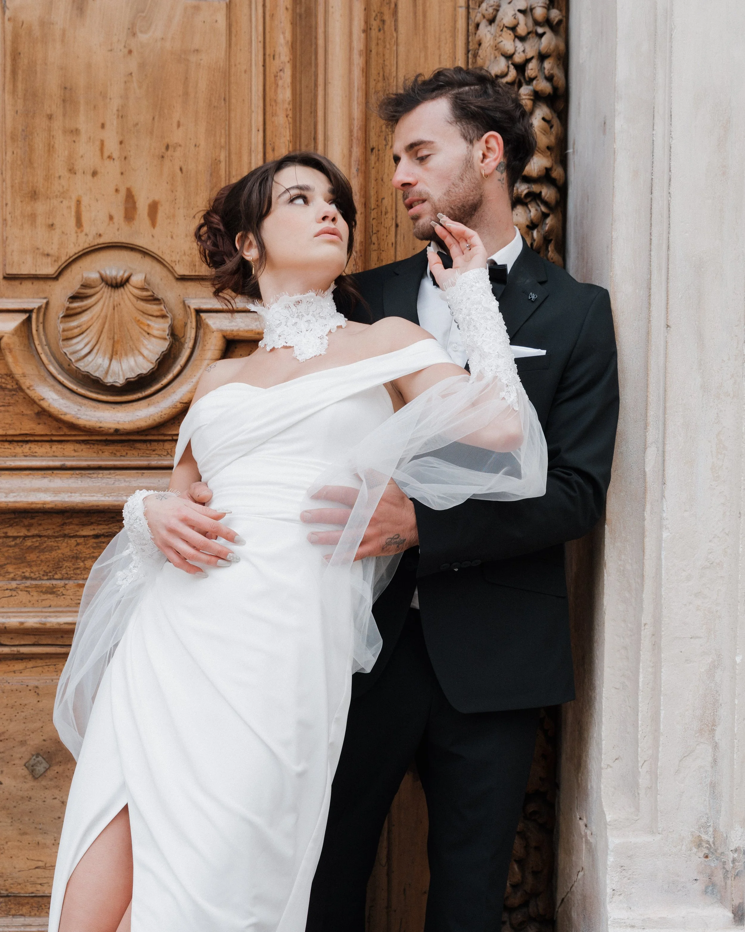 Un couple en vêtements de mariage posant contre un mur en bois, la femme en robe blanche et le homme en costume noir à Lyon 2ème à l'hôtel dieu à l'intercontinental 