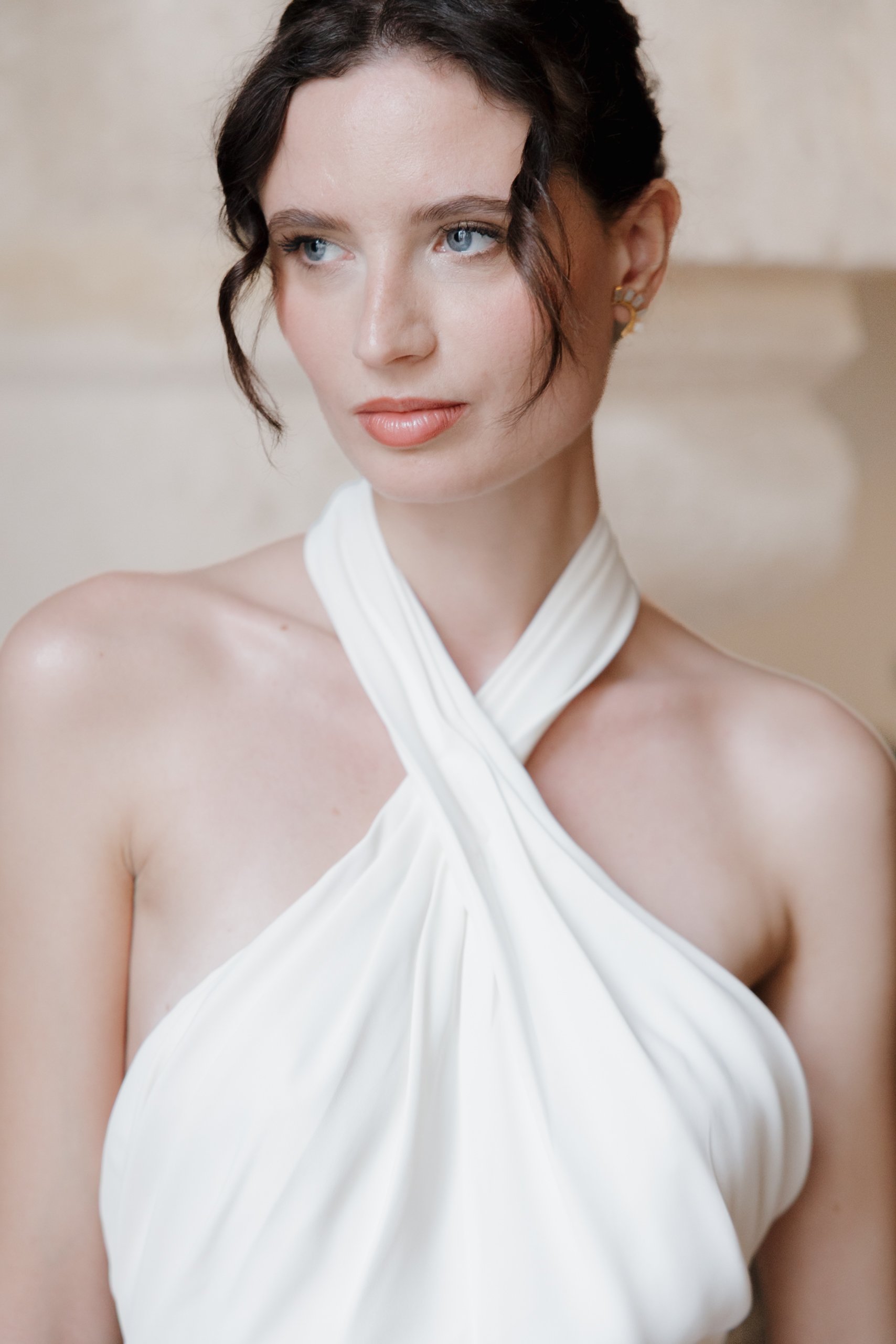 Une jeune femme aux cheveux bruns, yeux bleus, portant une robe blanche avec un col en tissu plissé. Session engagement paris, Louvre, mariage haut de gamme, destination wedding. Robe de mariées, madame a dit oui 