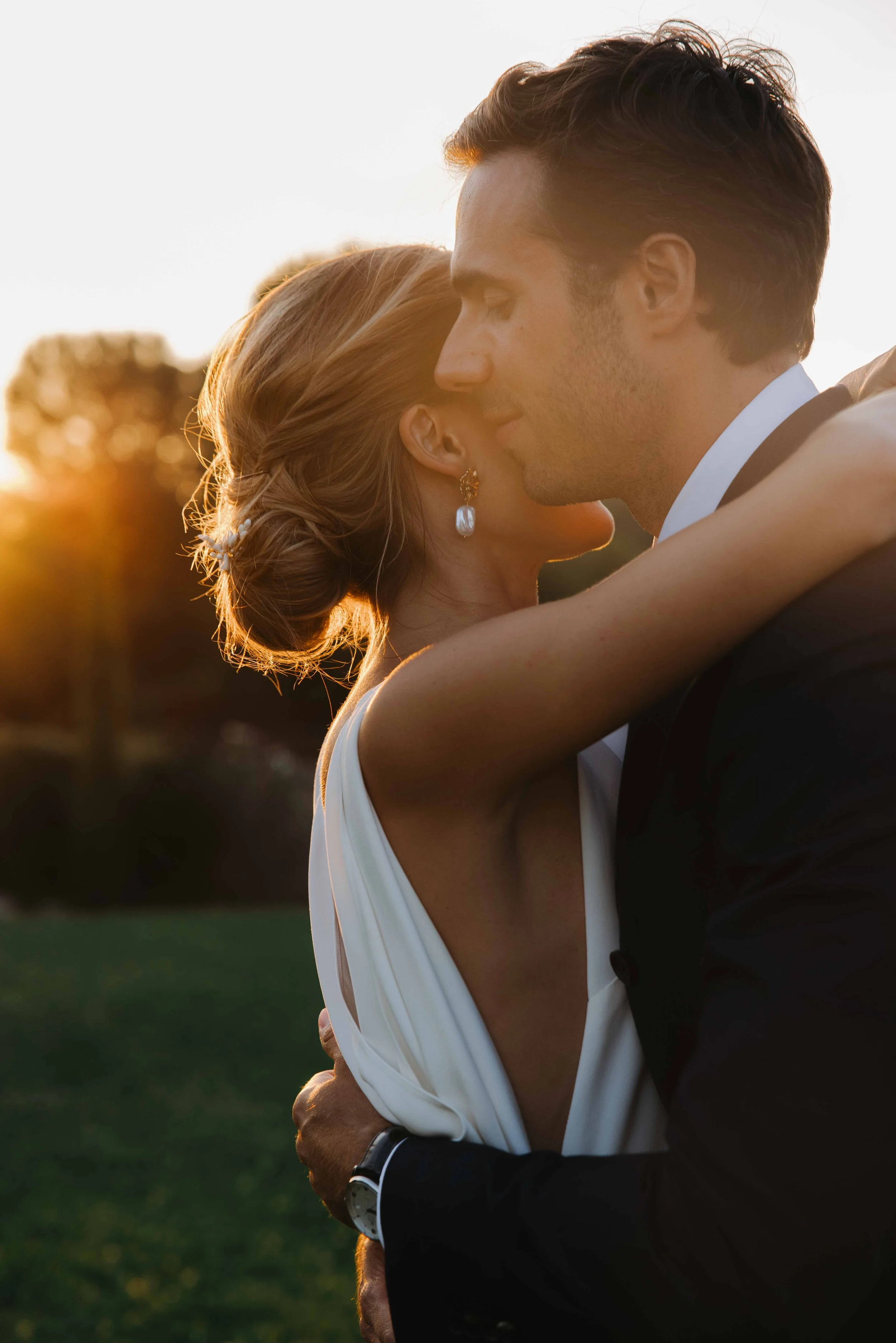 Un couple en robe de mariée et costume en train de s'embrasser lors d'un coucher de soleil en plein air. Domaine du bijoutier à grignan, drome provençal, coucher de soleil, session couple, mariage religieux, cérémonie laïque, photographe mariage sud 