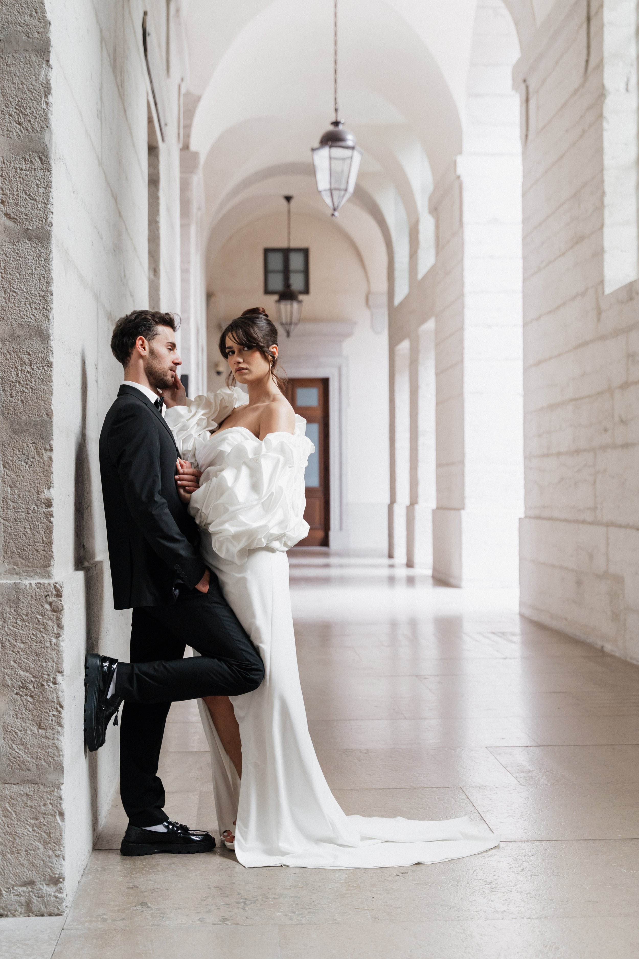 Un couple habillé en mariage dans un couloir en pierre avec des arches et des lanternes suspendues à Lyon 2ème à l'hôtel dieu à l'intercontinental 
