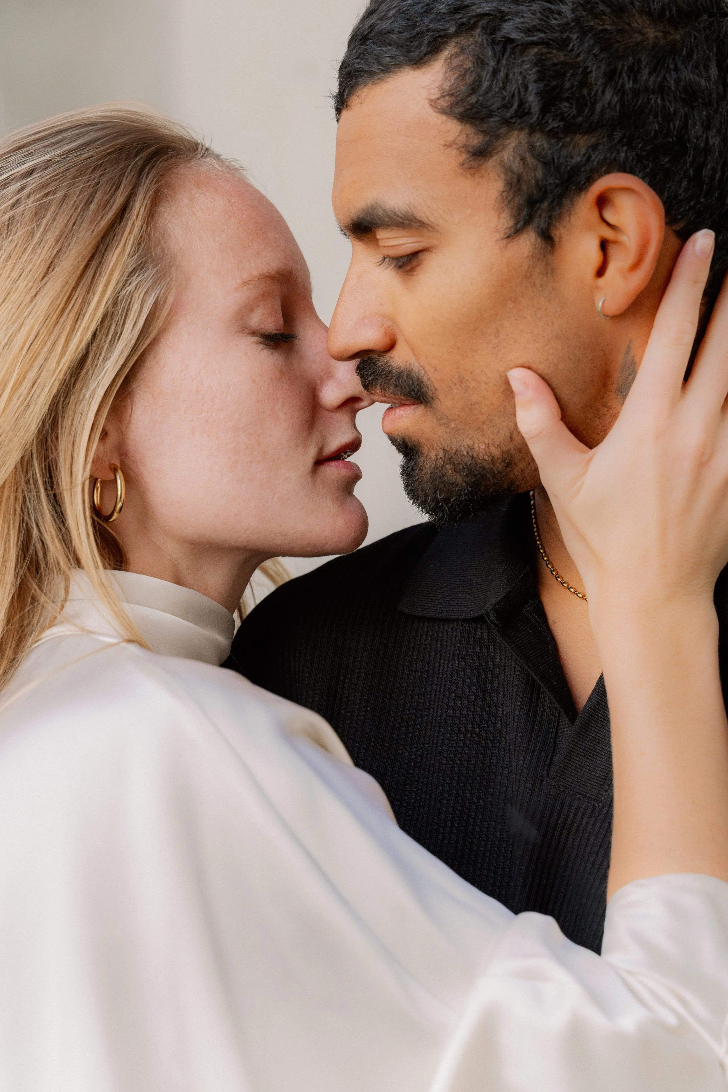 Un couple s'apprête à s'embrasser, très proche l'un de l'autre, avec les yeux fermés. La femme a les cheveux blonds et porte des boucles d'oreilles dorées, tandis que l'homme a des cheveux noirs, une barbe et porte un collier. à l'hôtel dieu à Lyon 2