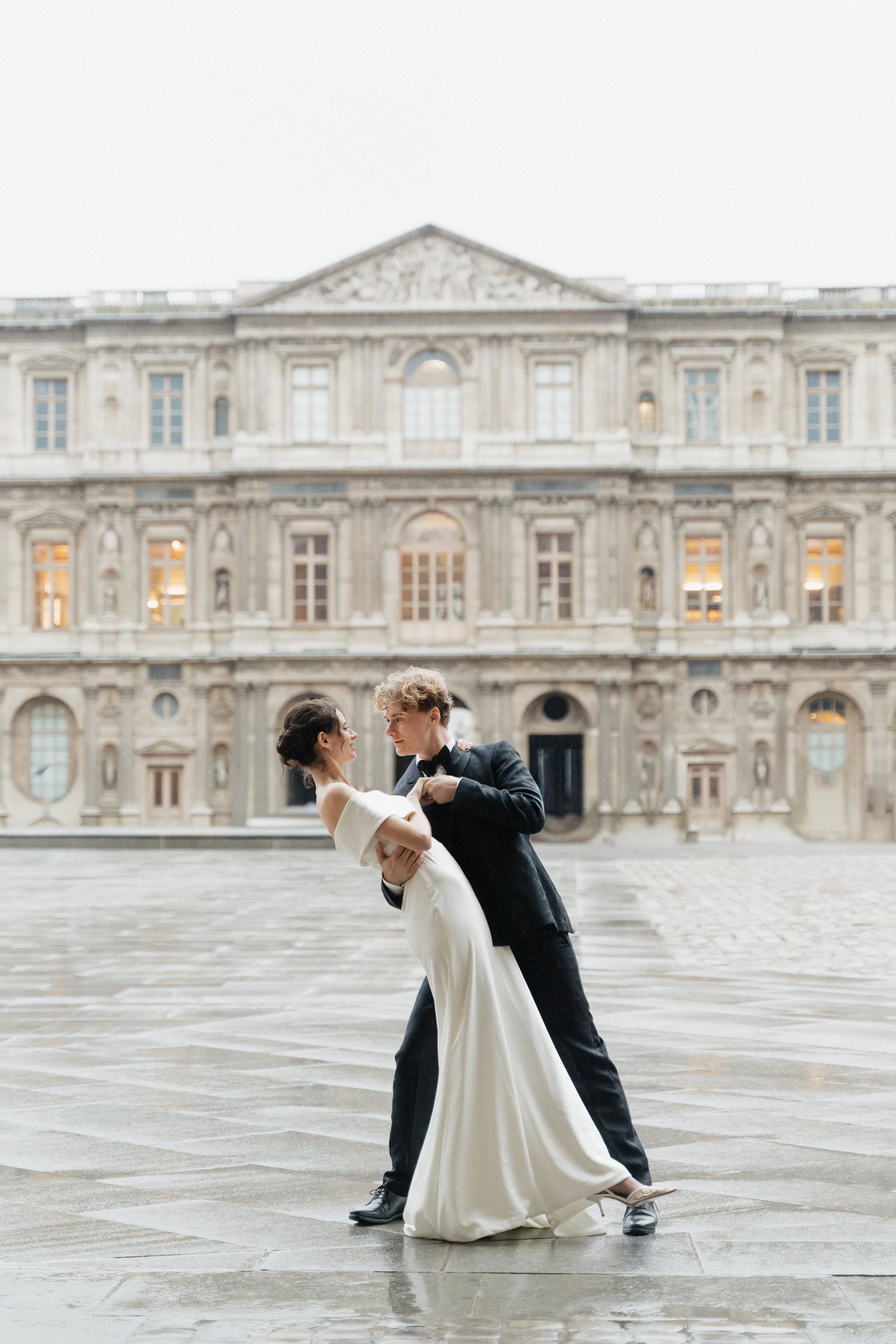 Shooting photo session engagement avec couple au Louvre à Paris, robe de mariés et costume de mariés homme, monument historique France, danse place du Louvre, photographe argentique et numérique 