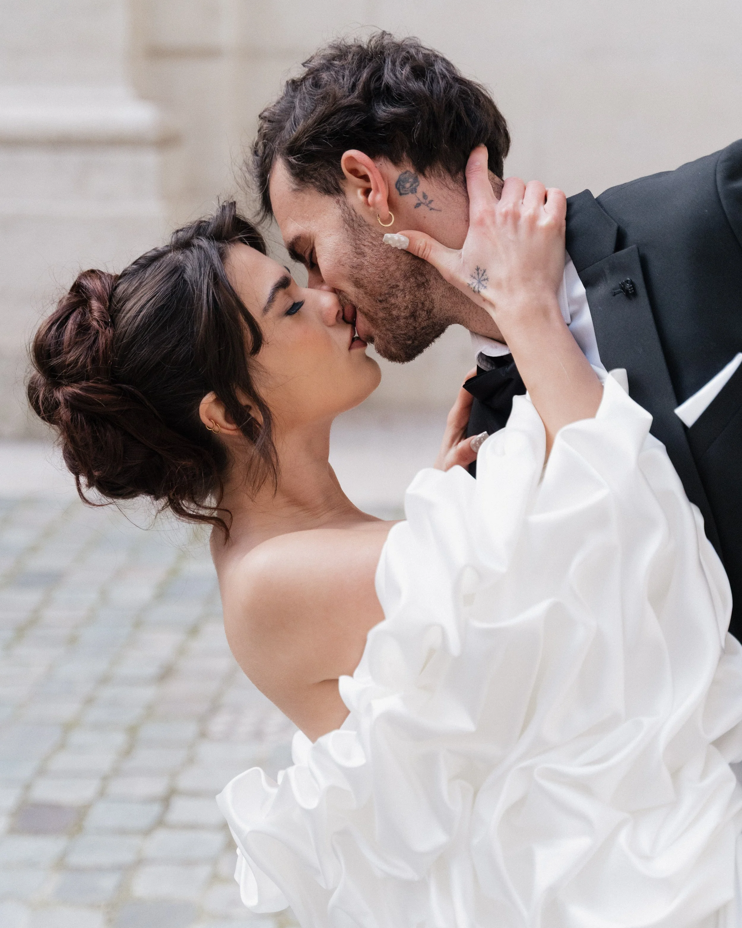Un couple en tenue de mariage s'embrassant passionnément, en extérieur sur un pavé à l'hôtel dieu à Lyon 2ème, à l'intercontinental, session engament.
