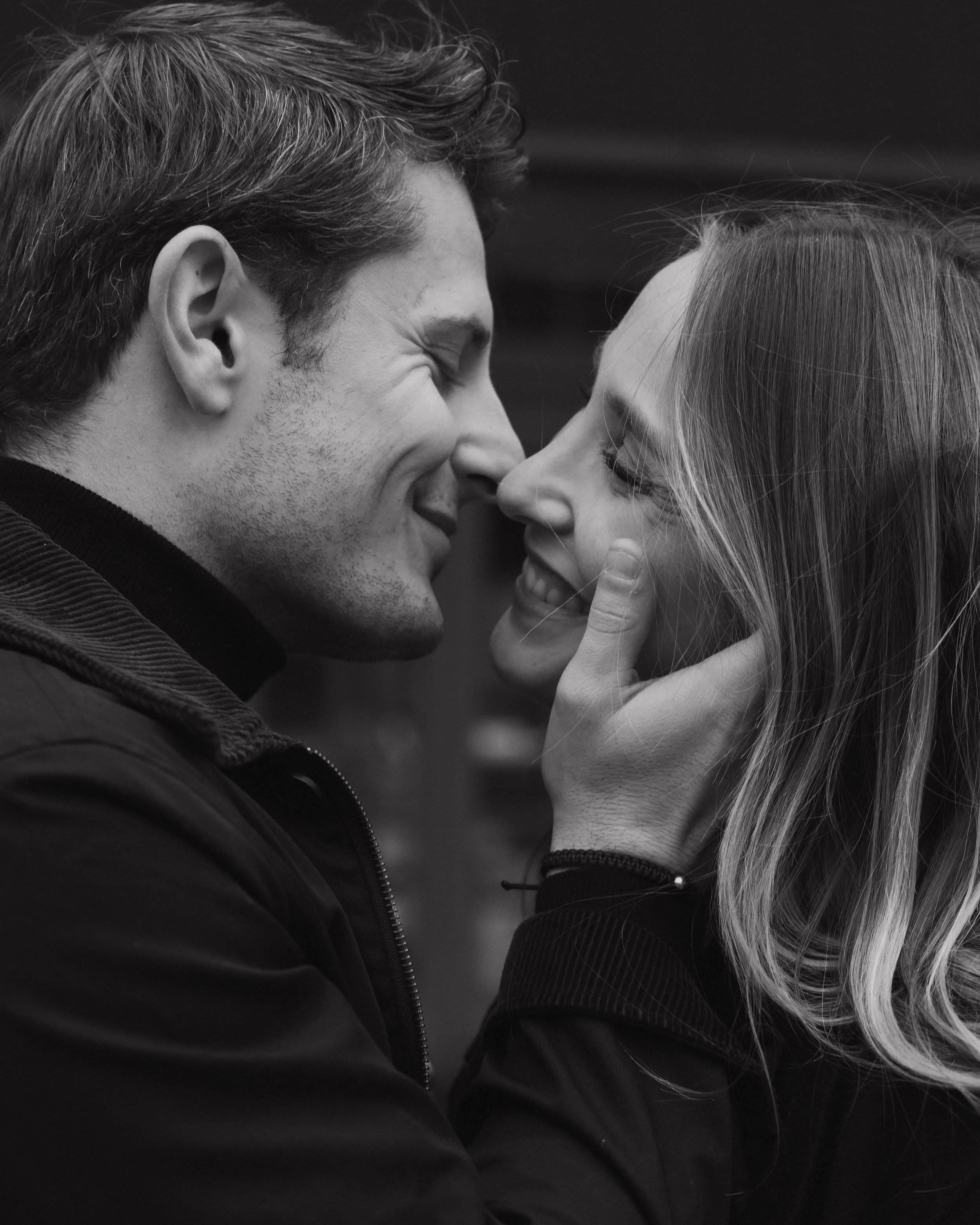 Un couple souriant et proche, se touchant le visage en silence, dans un cadre intime. session engagement couple Lyon 6eme, brotteaux, photographe mariage bordeaux et Lyon et destination wedding