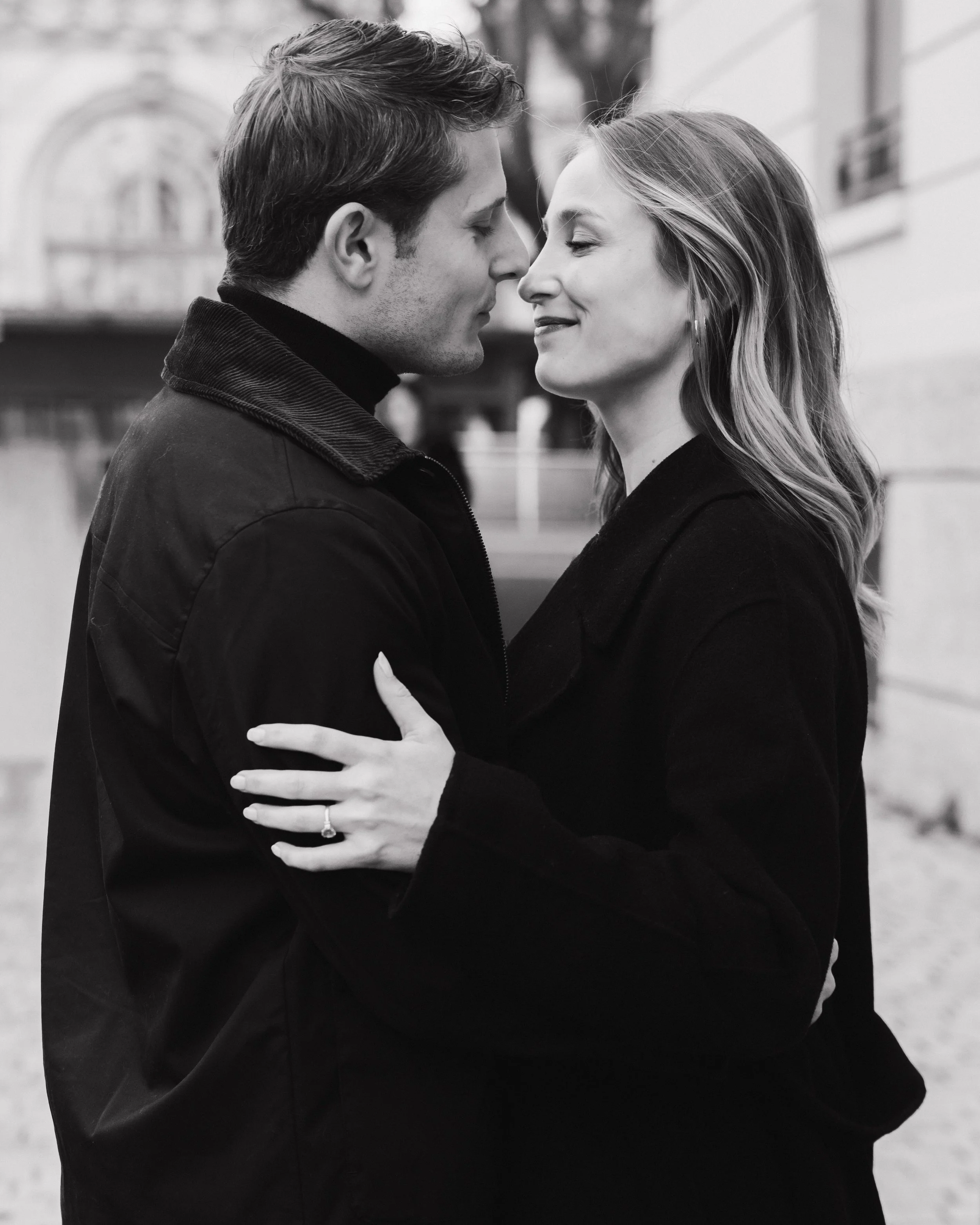 Un couple se tient très proche, avec leurs fronts touchant, dans un cadre urbain, en noir et blanc, exprimant une relation intime et amoureuse session engagement couple Lyon 6eme, brotteaux, photographe mariage bordeaux et Lyon et destination wedding