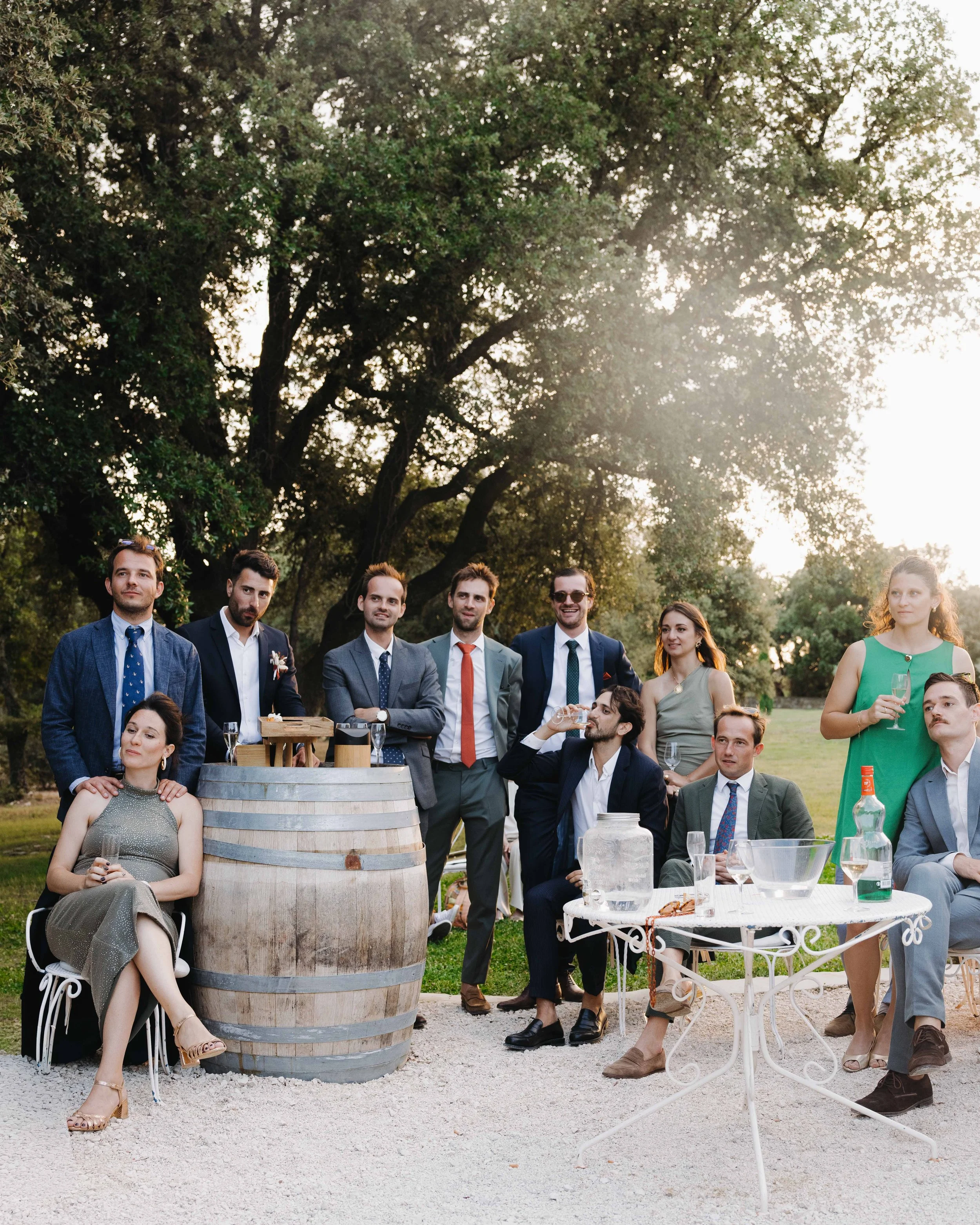 Groupe de personnes lors d'une célébration en plein air, avec des boissons et un décor naturel. Domaine du bijoutier à grignan, drome provençal, coucher de soleil, session couple, mariage religieux, cérémonie laïque, photographe mariage sud 