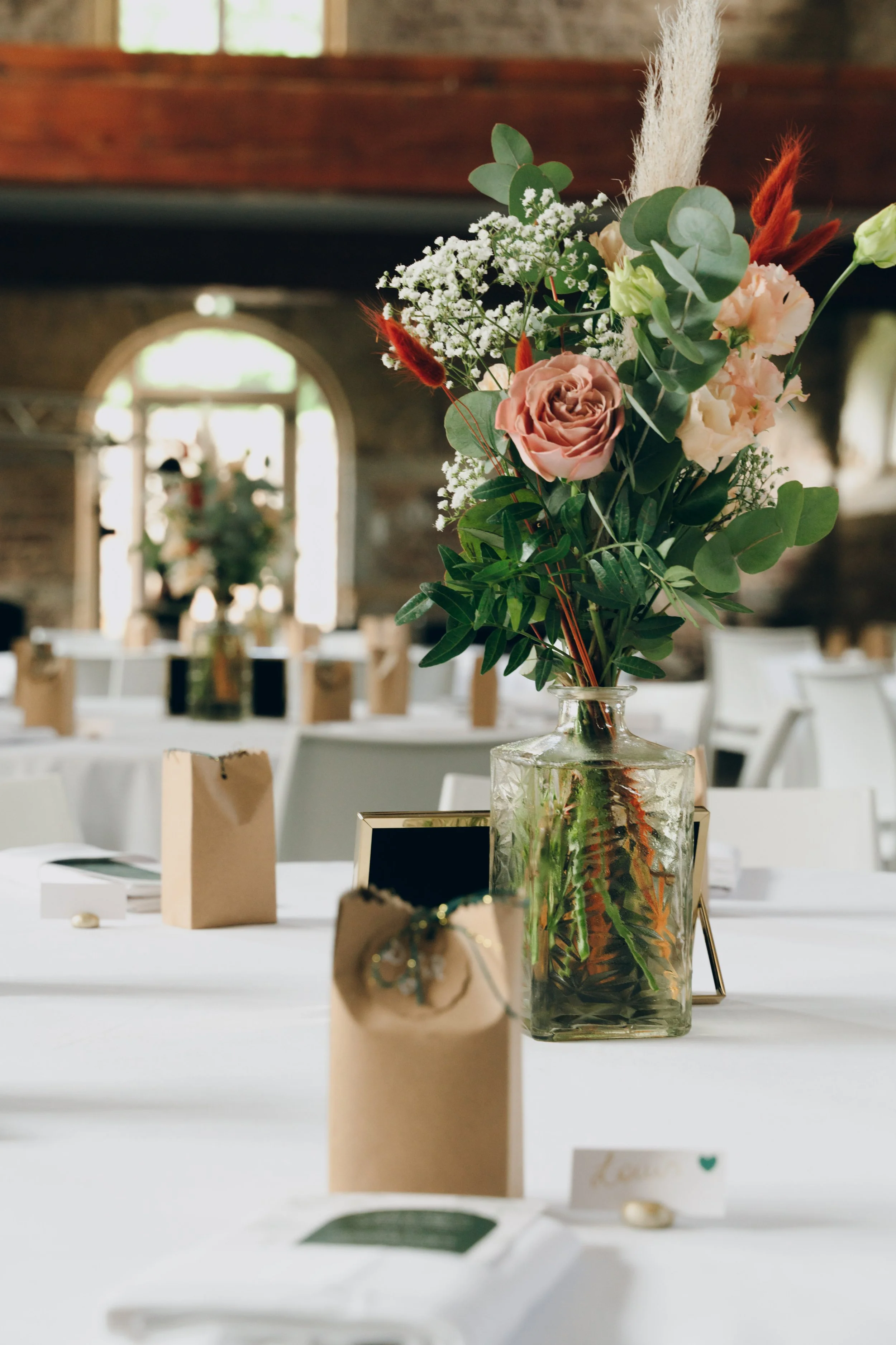 Bouquet de fleurs colorées sur une table décorée pour un événement, avec des places assises et des boîtes-cadeaux. Domaine de tourieux à Savigny dans le beaujolais à Lyon. Mariage cérémonie laïque, photographe Lyon haut de gamme, duo photographe 