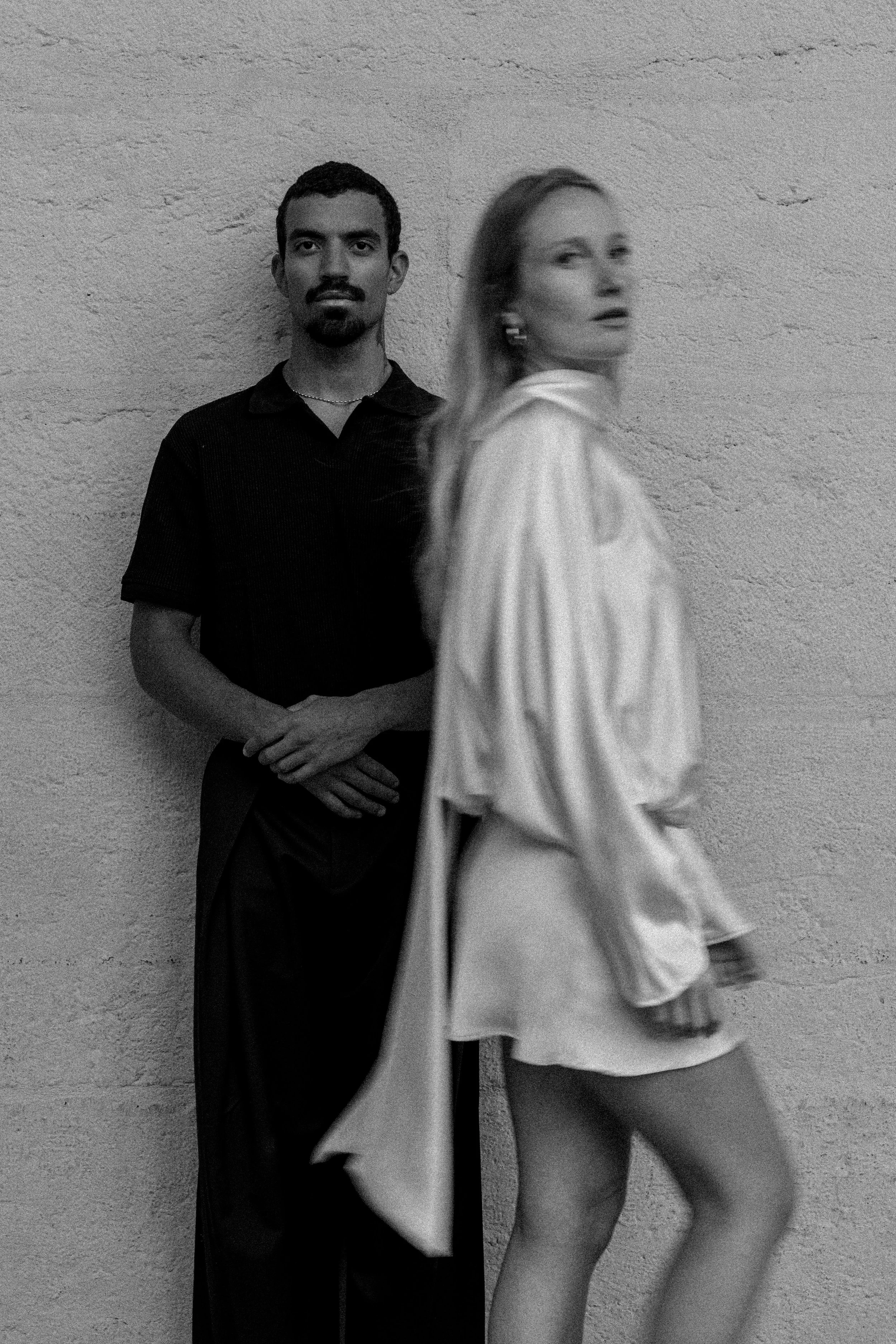 Deux personnes, un homme en arrière-plan et une femme en avant-plan, posant contre un mur en béton, en noir et blanc à l'hôtel dieu à Lyon 2ème, à l'intercontinental, session engament, photographe mariage duo haut de gamme.