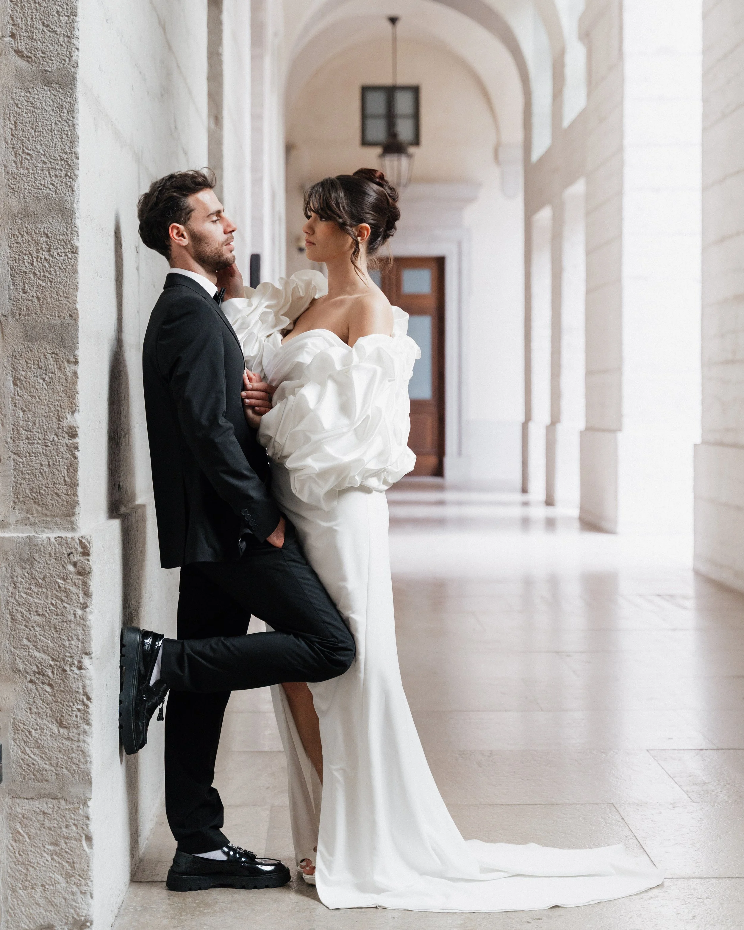 Un couple de mariés en tenues de mariage modernes dans un couloir élégant en pierre claire à Lyon 2ème à l'hôtel dieu à l'intercontinental 