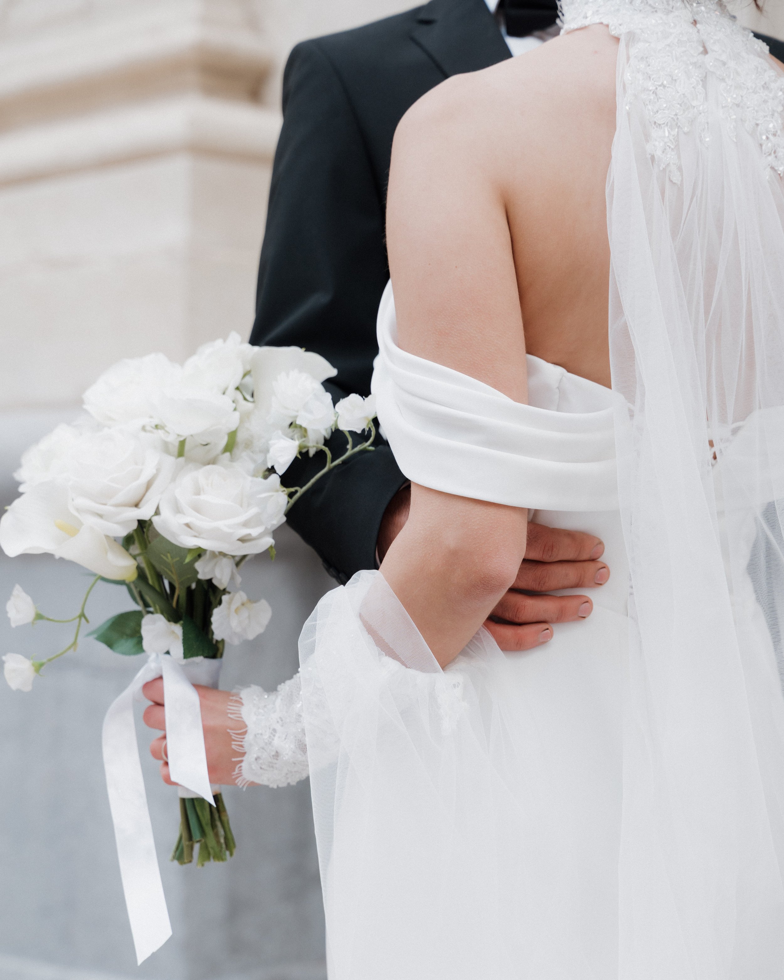 Un couple de mariés lors de leur mariage, la femme en robe blanche avec voile et le homme en smokings noir, la femme tient un bouquet de fleurs blanches à Lyon 2ème à l'hôtel dieu à l'intercontinental 