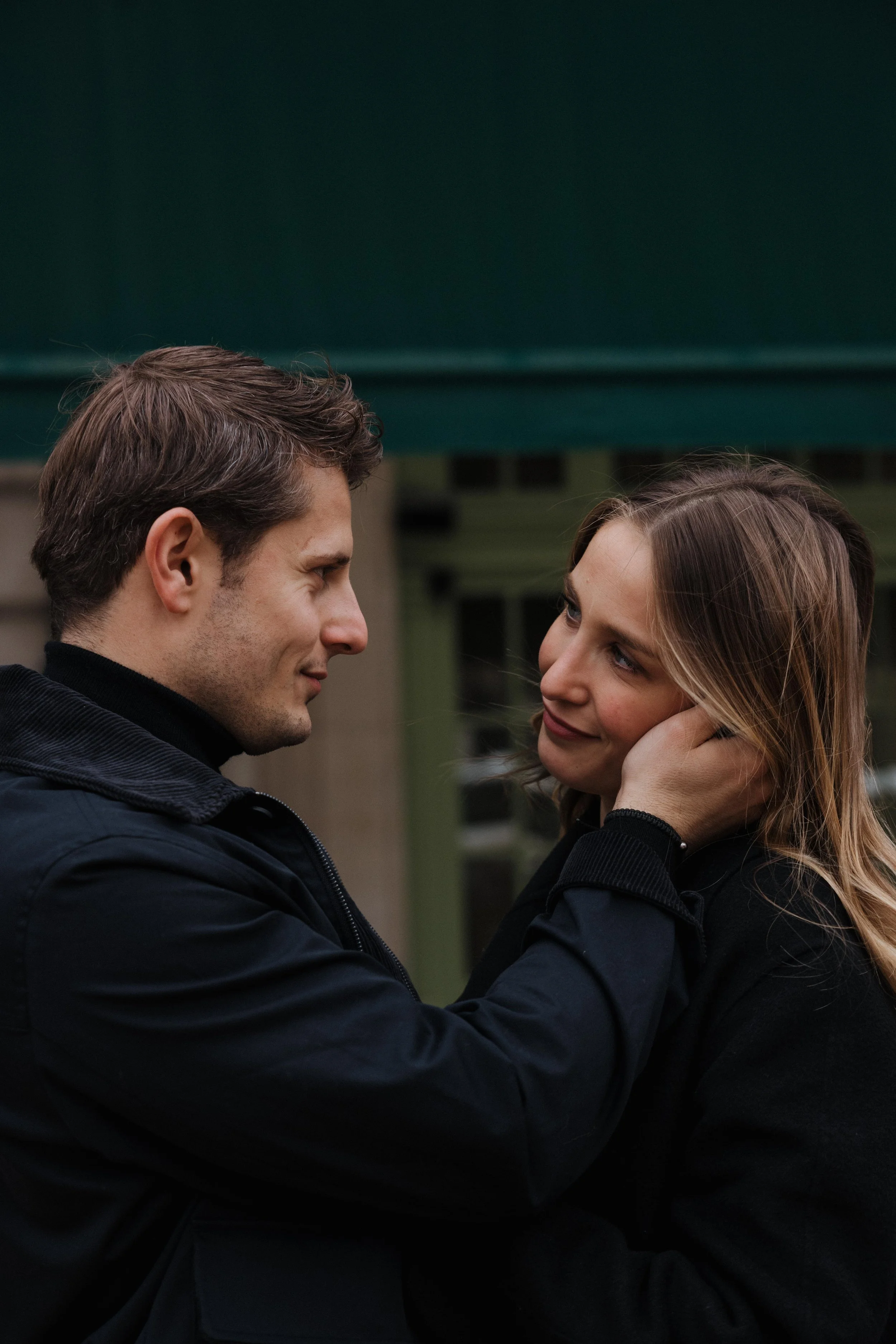 Un homme et une femme regardent tendrement, l'homme tenant la joue de la femme dans un geste affectueux. session engagement couple Lyon 6eme, brotteaux, photographe mariage bordeaux et Lyon et destination wedding