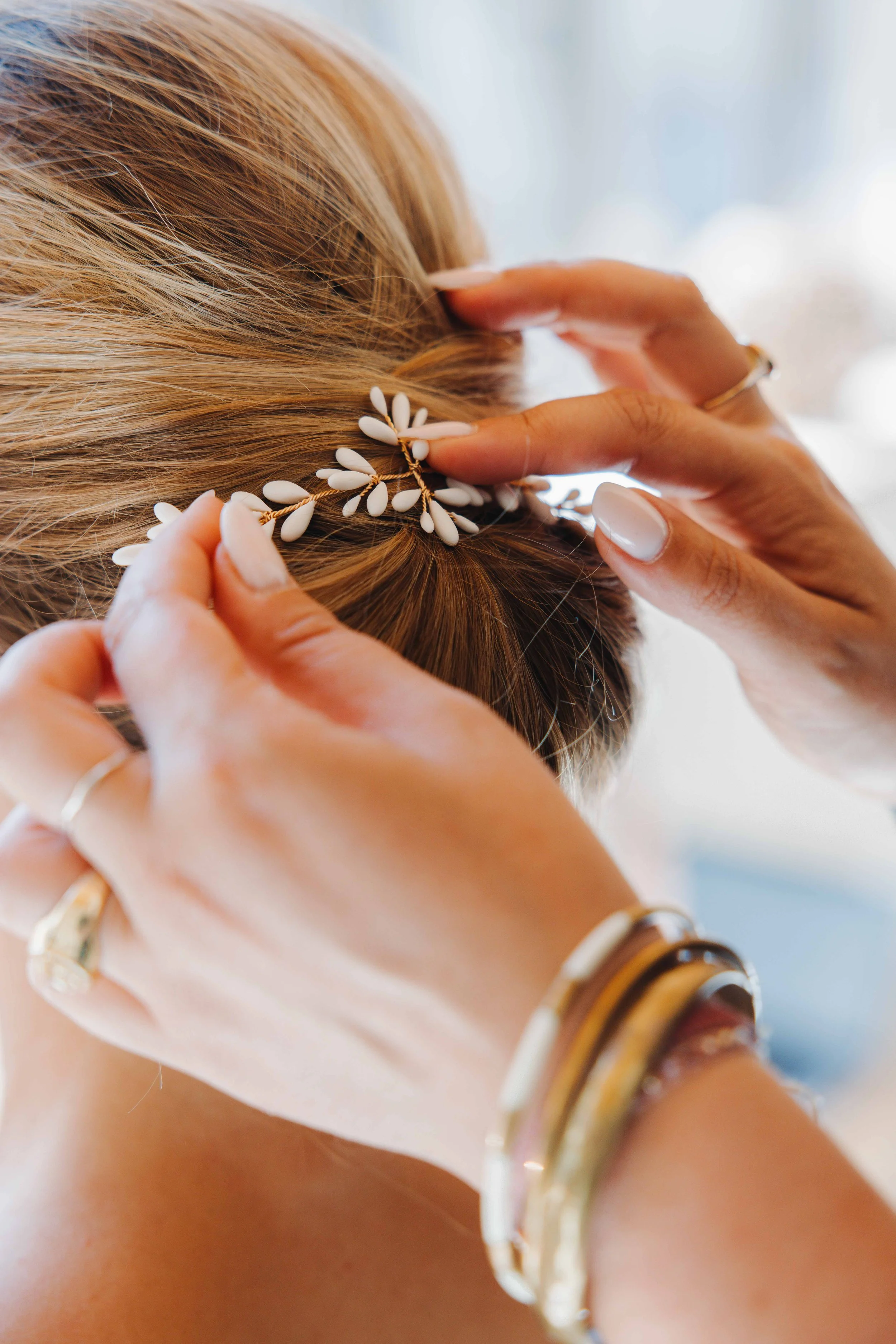 Une personne place un peigne décoratif avec des motifs floraux dans ses cheveux blonds. Domaine du bijoutier à grignan, drome provençal, coucher de soleil, session couple, mariage religieux, cérémonie religieuse 