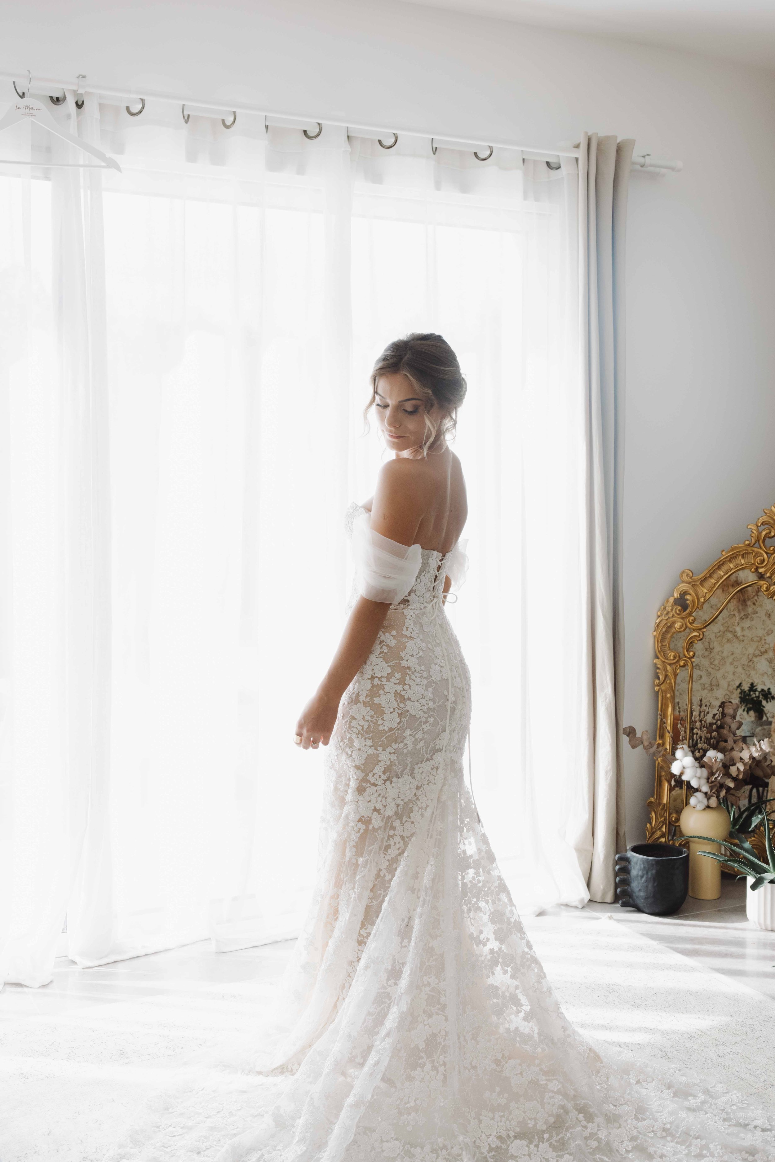 Noémie qui est debout devant une fenêtre lors des préparatifs du mariage civil et laïque à côté de Lyon en rhone alpes