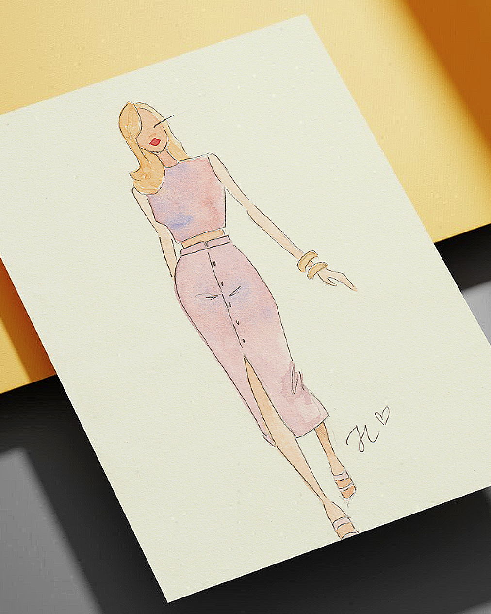 Watercolor fashion illustration of a woman in a pink dress with a high slit, wearing strappy sandals and gold bangles, signed with initials and a heart.