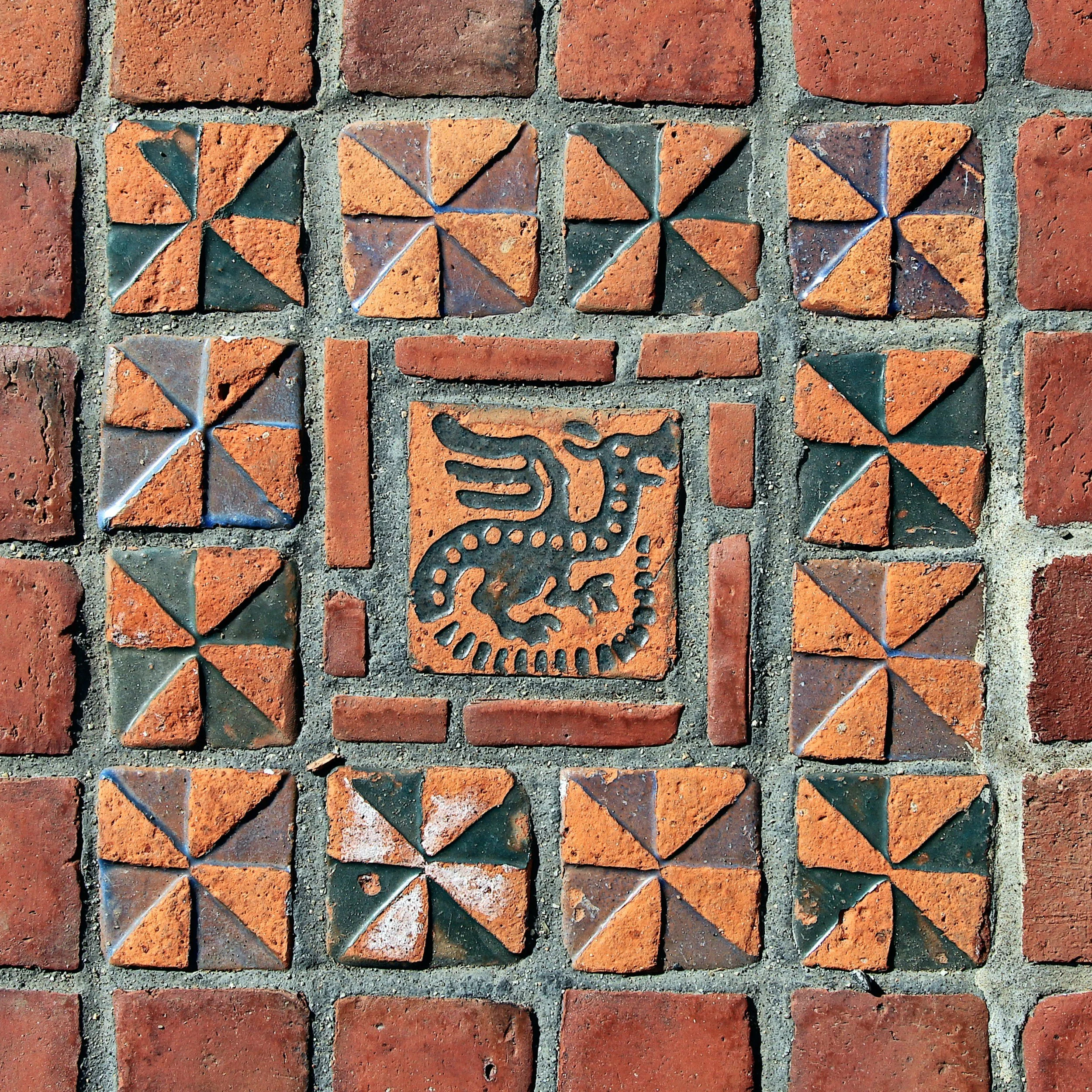 Decorative brick and tile wall with a central tile featuring an engraved dragon design.