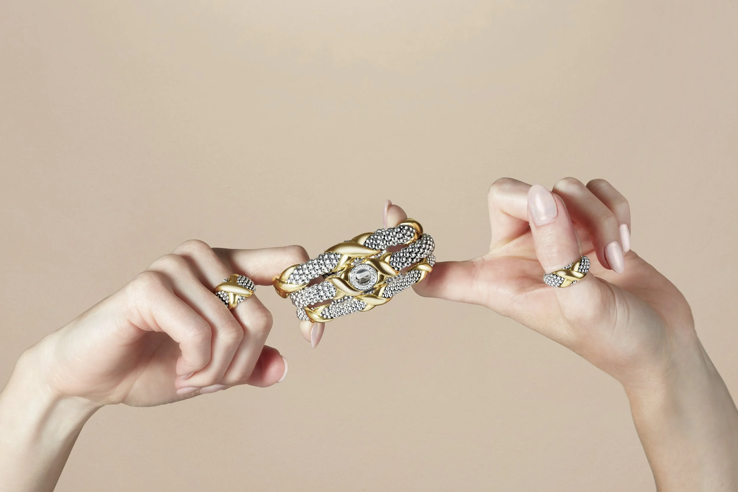 Hands holding multiple gold and rhinestone jewelry pieces, including rings and a statement bracelet