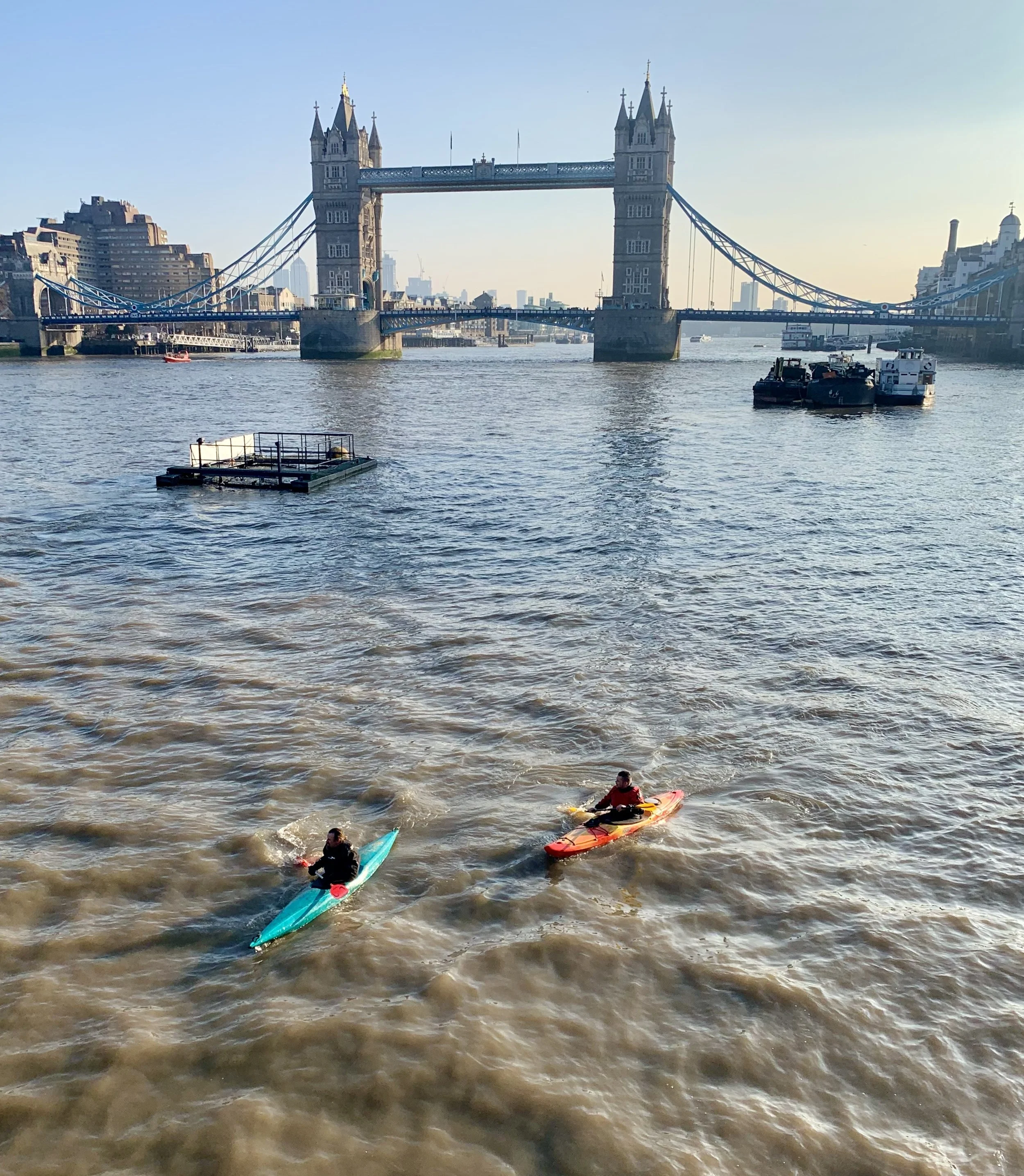 Two people kayaking on the River Thames in London with Tower Bridge in the background.