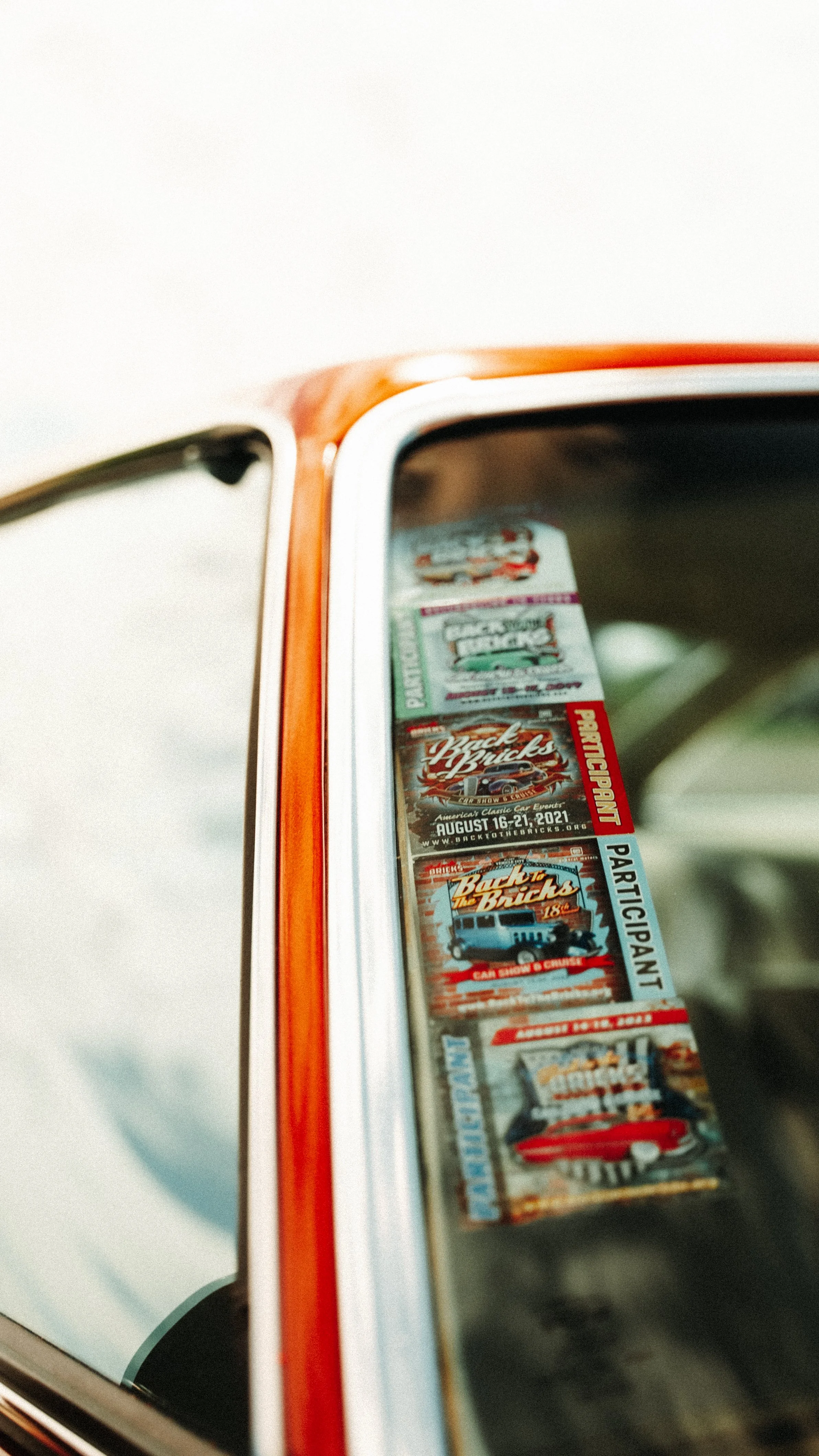 Close-up of car window with vintage stickers for car shows and events.