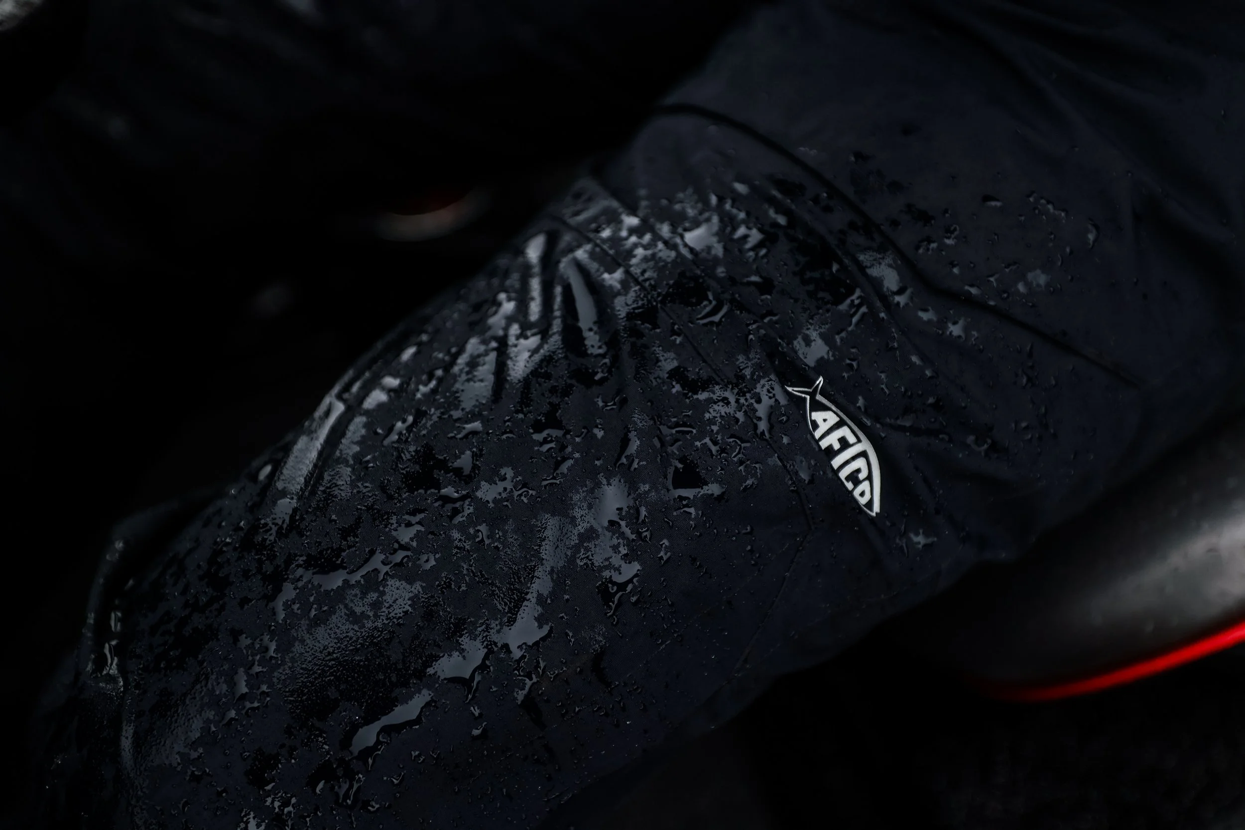 Close-up of a black Nike athletic shoe with water droplets on the surface and the Nike logo visible.