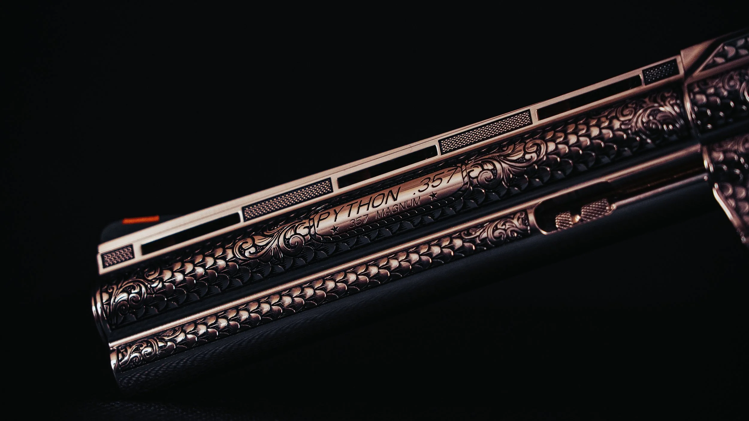 Close-up of a detailed, ornate gun slide with engraving that reads 'Python .357 Magnum' on a black background.