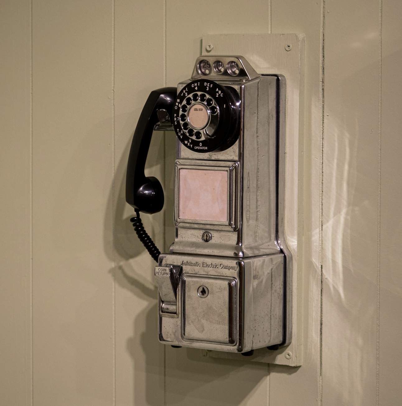 A vintage payphone mounted on a beige wall.
