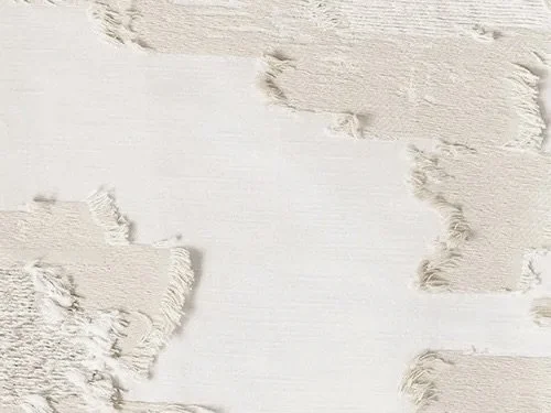 Close-up of a wooden surface painted in different shades of white and beige, with some areas showing peeling paint.