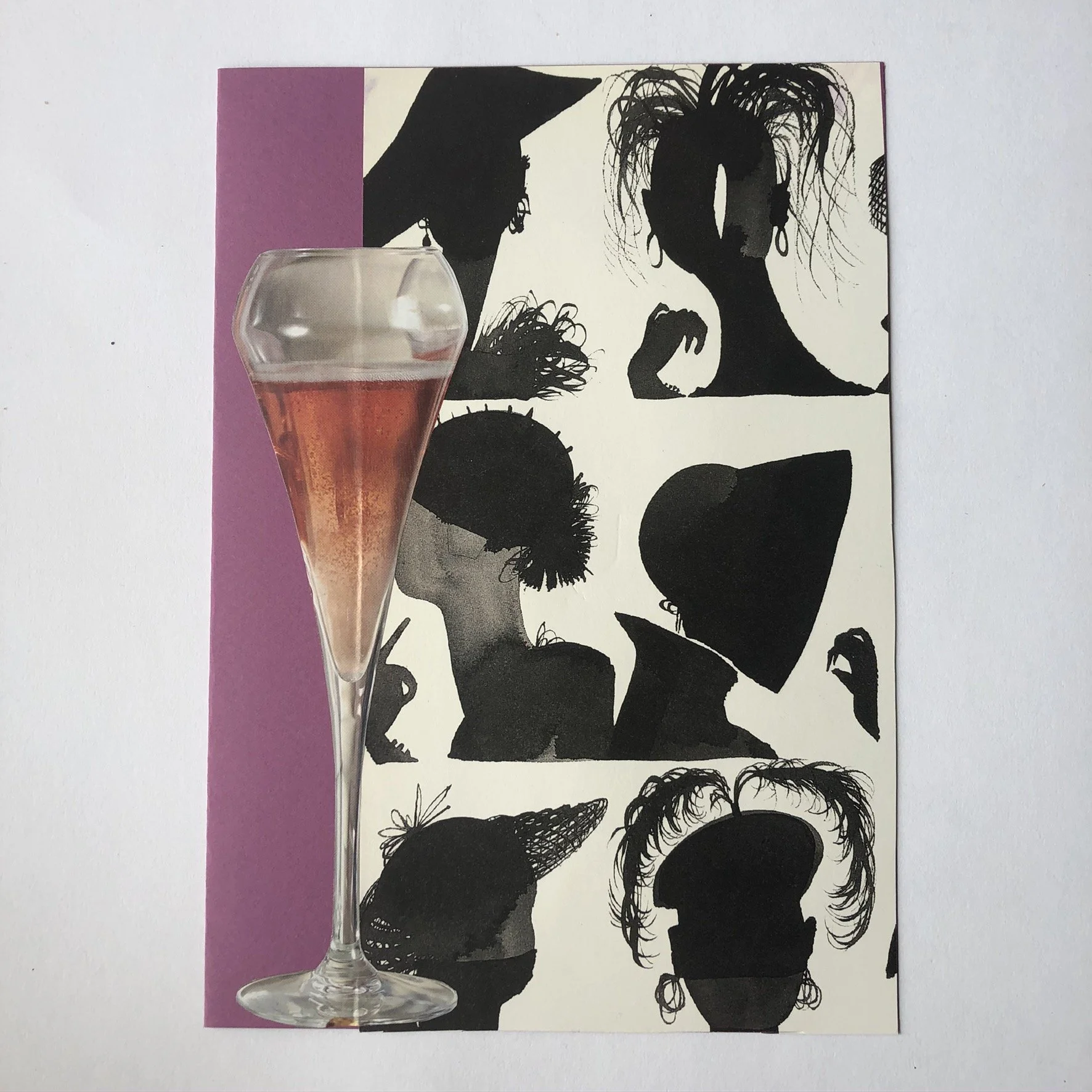 A clear champagne flute filled with pink liquid placed on a black and white silhouette-style collage of women's hairstyles and accessories on a sheet of paper with a purple edge.