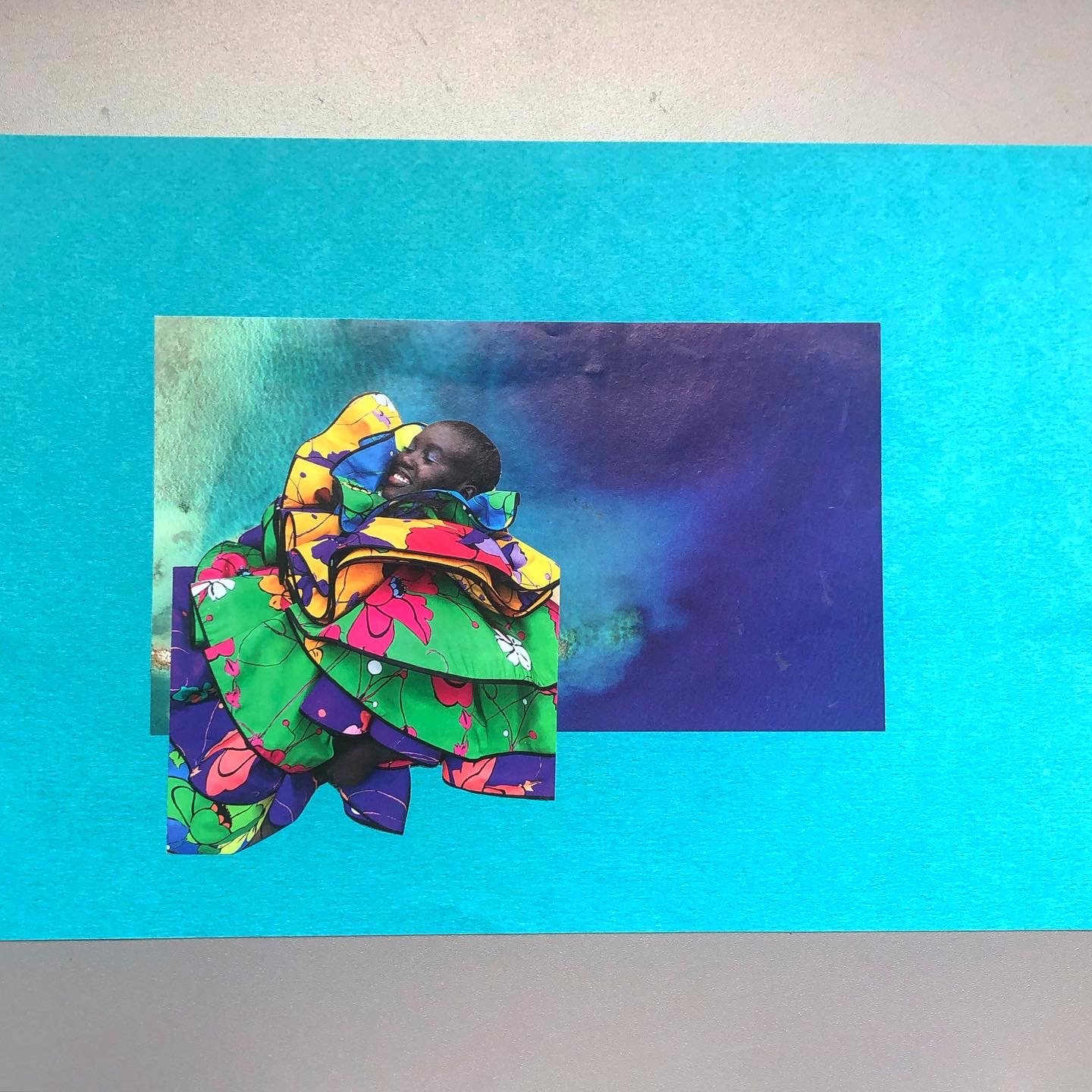 Digital collage of a person with dark skin and short hair, wrapped in vibrant, patterned fabric featuring flowers, against a colorful abstract background.