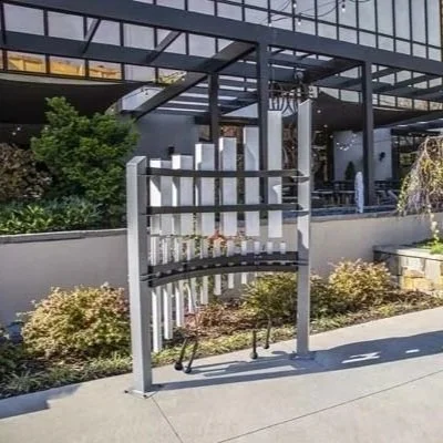 A modern bike rack with vertical white bars and a black frame located outside a building.