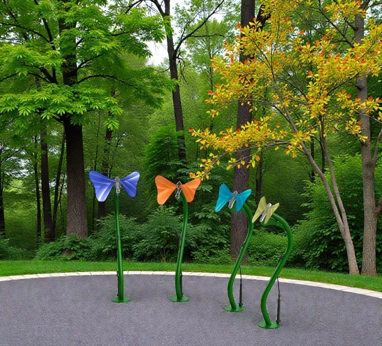 Colorful butterfly-shaped sculptures on green stems in a park with lush trees and grass