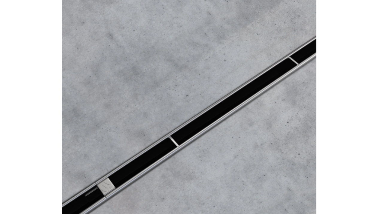 Close-up of a linear drain with black grate cover on a concrete surface.